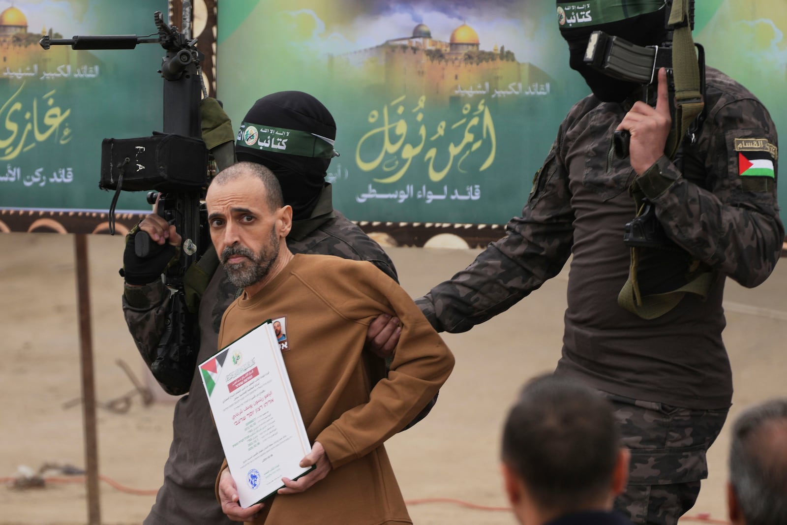 Israeli captive Eli Sharabi, who has been held hostage by Hamas in Gaza since October 7, 2023, is escorted by Hamas fighters before being handed over to the Red Cross in Deir al-Balah, central Gaza Strip, Saturday Feb. 8, 2025. (AP Photo/Abdel Kareem Hana)