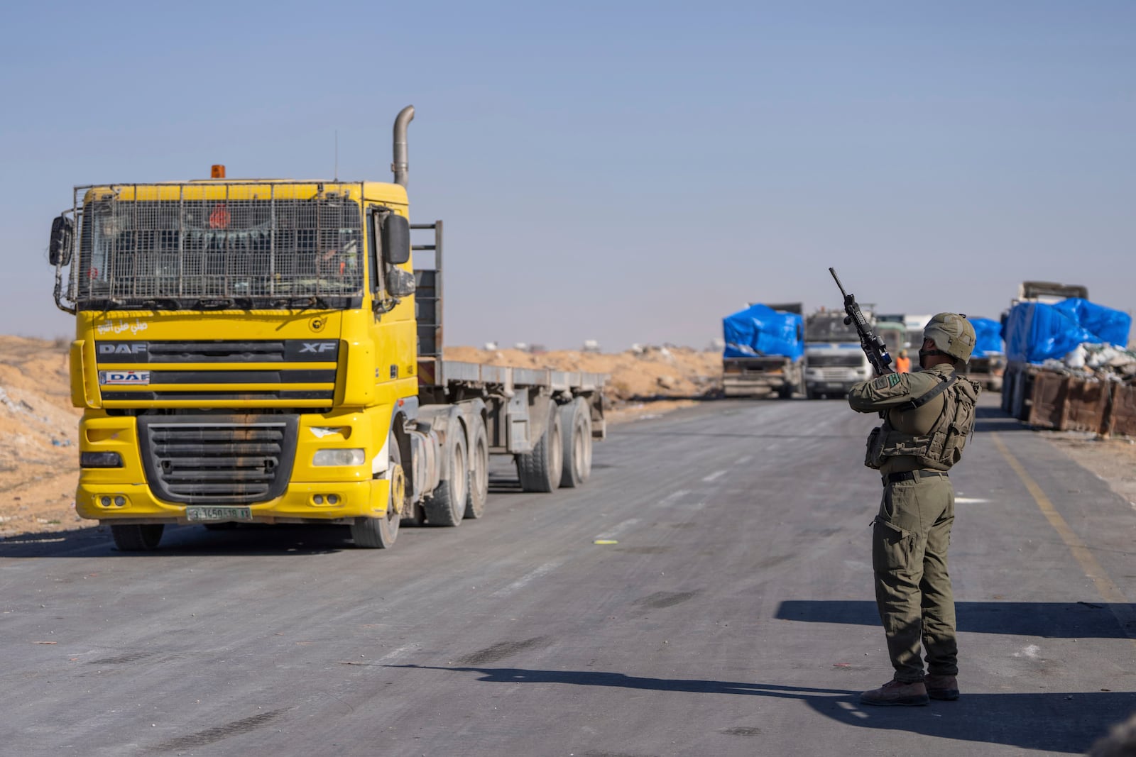 An Israeli soldier stands guard on the Palestinian side of the Kerem Shalom aid crossing as reporters tour the area in the Gaza Strip, Thursday, Dec. 19, 2024. (AP Photo/Ohad Zwigenberg)