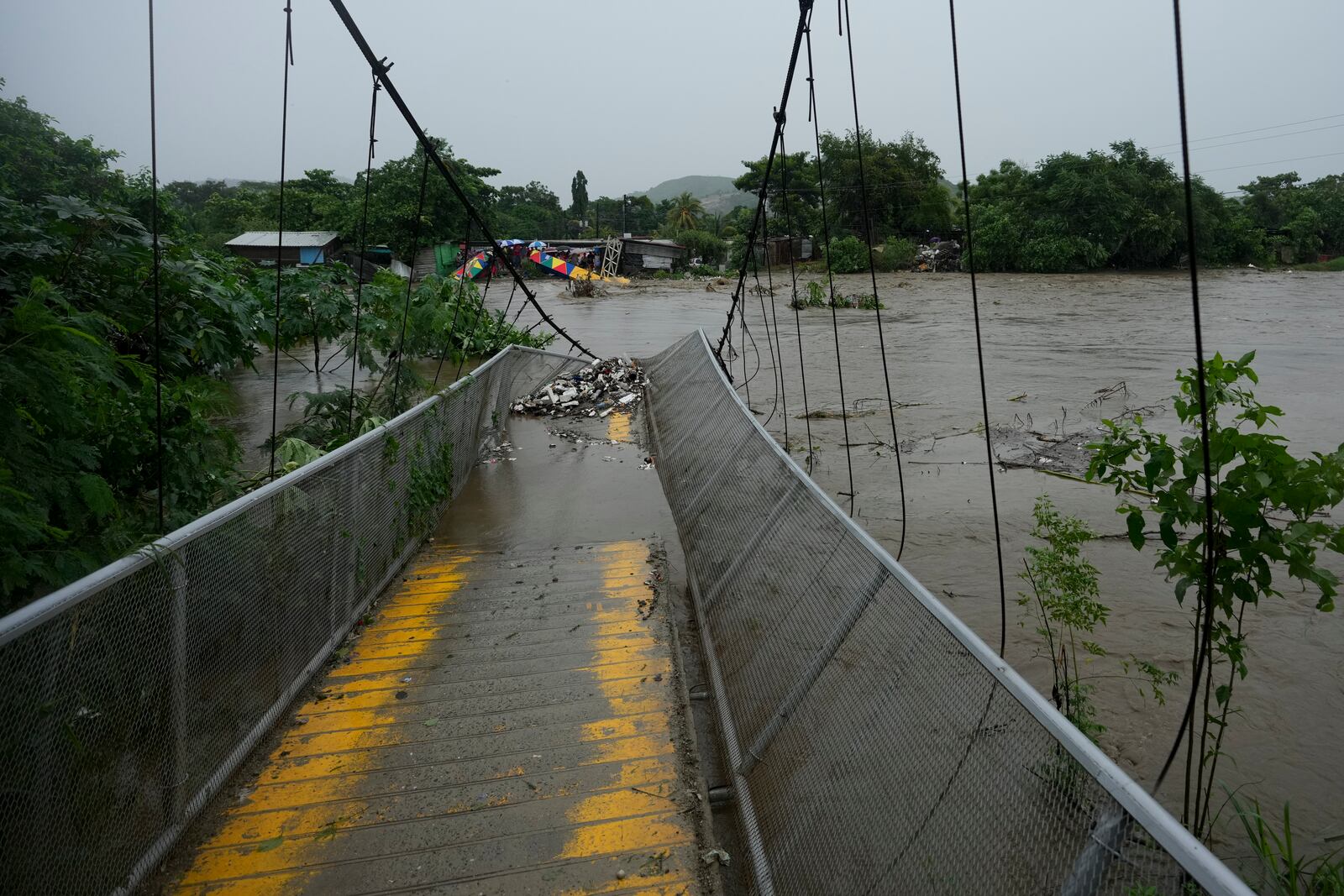 A pedestrian bridge collapsed due to flooding caused by rains brought on by Tropical Storm Sara in San Pedro Sula, Honduras Saturday, Nov. 16, 2024. (AP Photo/Moises Castillo)