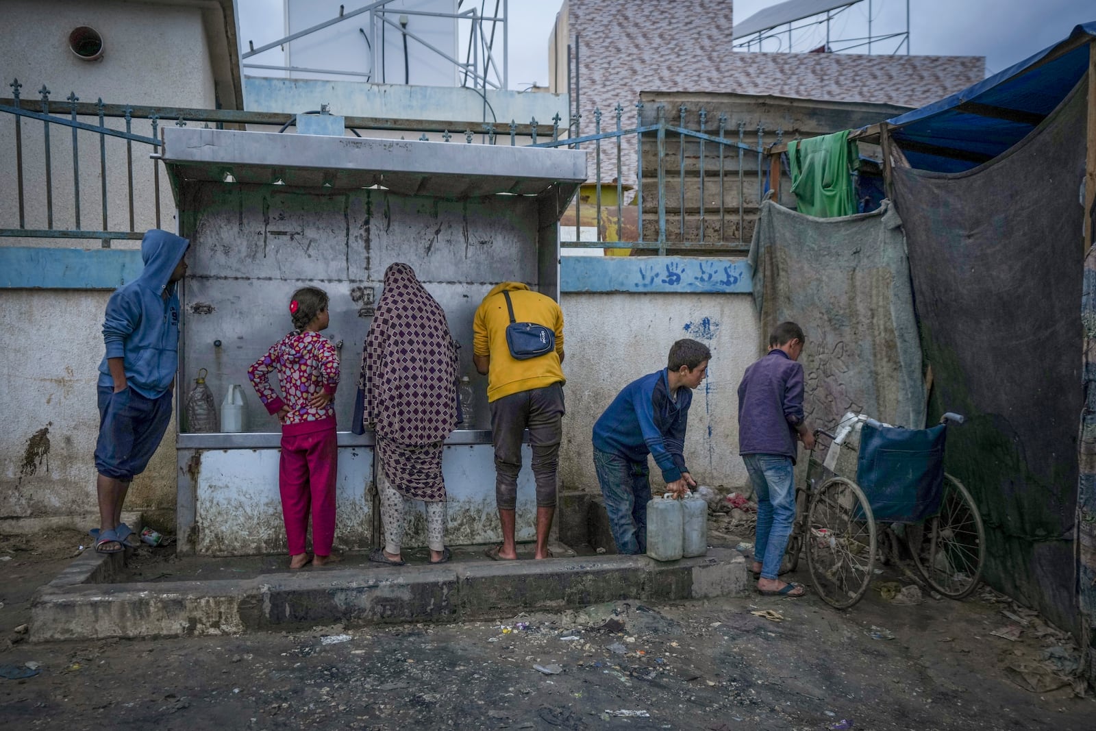 Palestinian children collect water in jerrycans at a camp for displaced people in Deir al-Balah, Gaza Strip, Thursday, Dec. 12, 2024. (AP Photo/Abdel Kareem Hana)