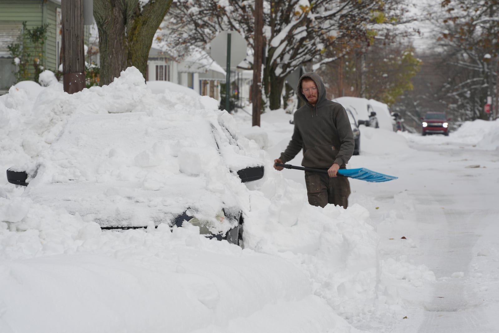 Matthew Jewell helps shovel snow off his father's car on the side street in Erie, Pa., Monday, Dec 2, 2024. AP Photo/Gene J. Puskar)