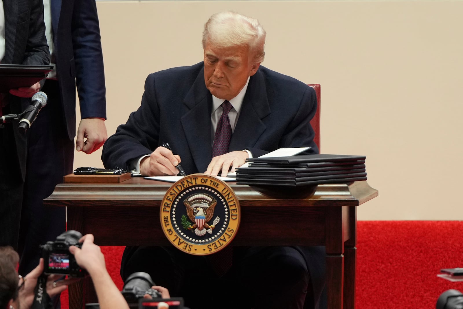 President Donald Trump signs an executive order at an indoor Presidential Inauguration parade event in Washington, Monday, Jan. 20, 2025. (AP Photo/Matt Rourke)