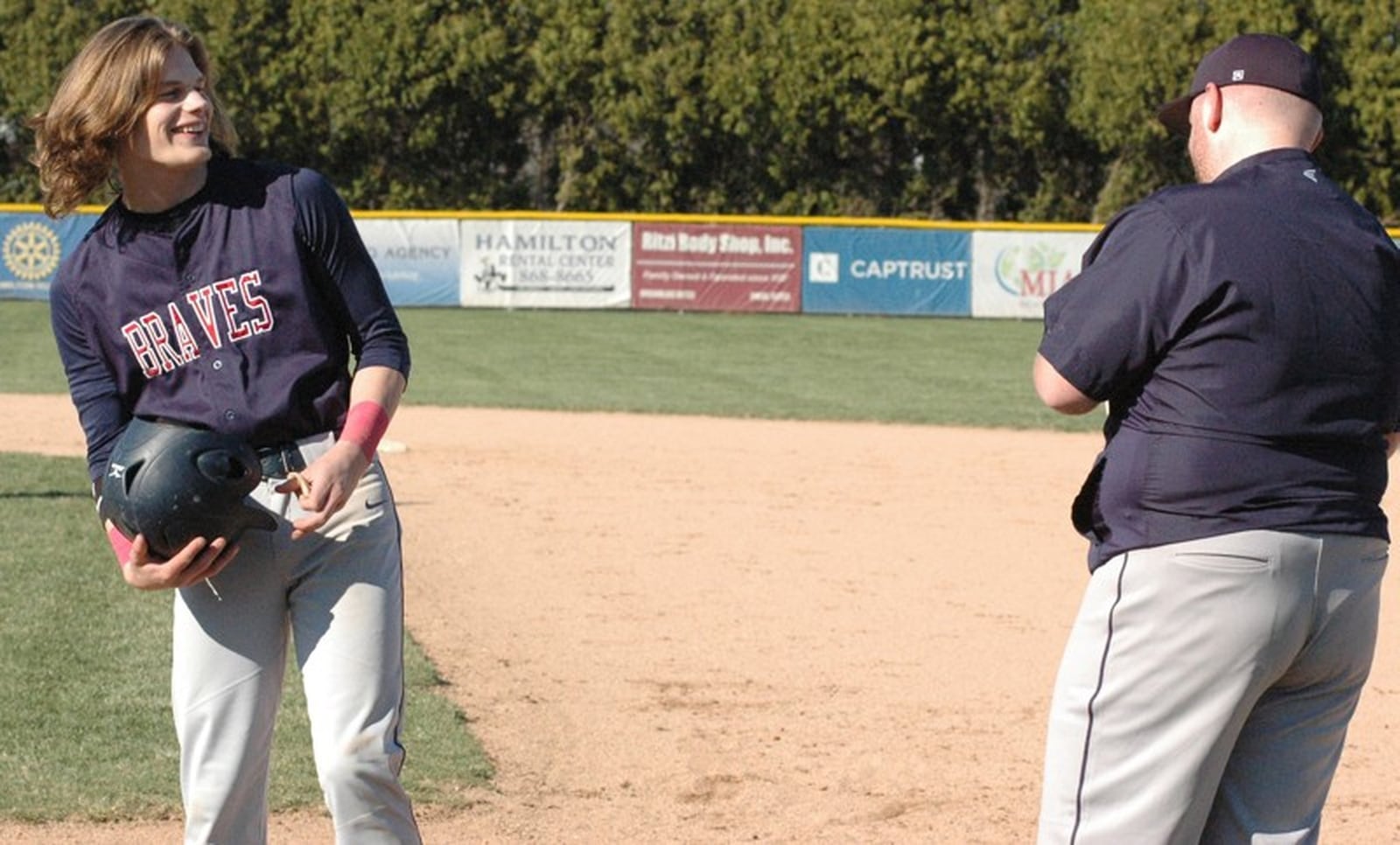 Talawanda’s Clayton Detherage shares a laugh with first-base coach Jimmy Joe Reed on April 2 during a Butler County baseball game against Badin at Alumni Field in Joyce Park. Badin won 4-3. RICK CASSANO/STAFF