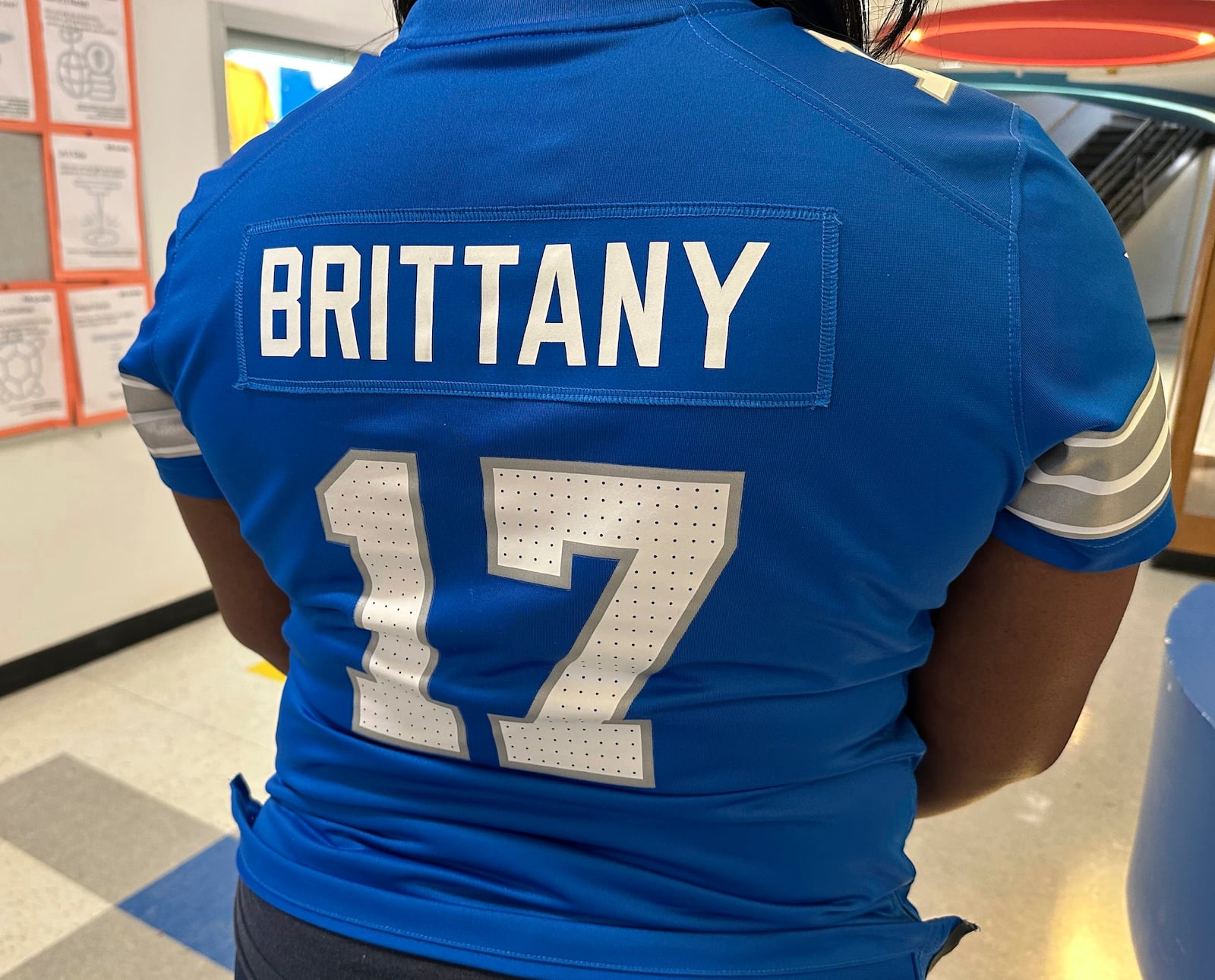 Brittany Sayles, assistant principal at Ann Arbor STEAM, displays the back of the personalized NFL football Detroit Lions jersey she wore to school Thursday, Jan. 16, 2025, in Ann Arbor, Mich. (AP Photo/Mike Householder)