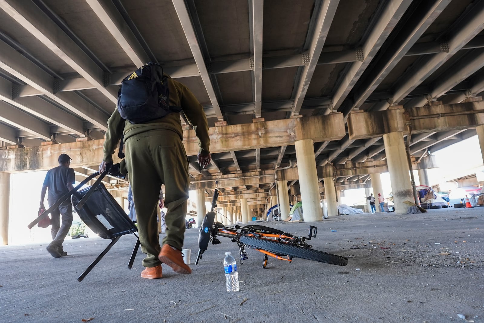 People living in a homeless encampment pick up belongings after Louisiana State police gave instructions for them to move to a different pre-designated location as they perform a sweep in advance of a Taylor Swift concert in New Orleans, Wednesday, Oct. 23, 2024. (AP Photo/Gerald Herbert)