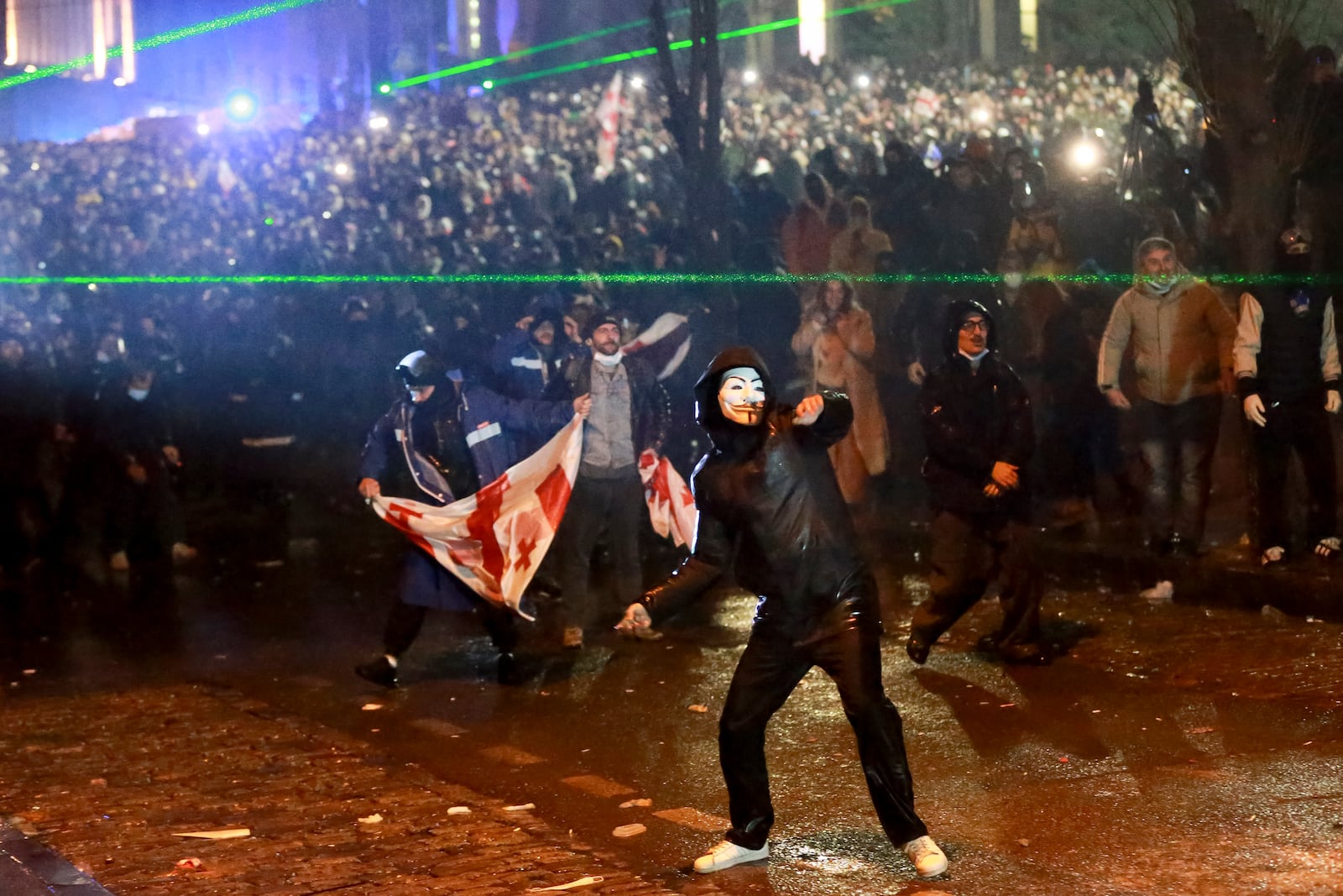 A masked demonstrator throws an object toward police during a rally against the governments' decision to suspend negotiations on joining the European Union for four years, outside the parliament's building in Tbilisi, Georgia, on Sunday, Dec. 1, 2024. (AP Photo/Zurab Tsertsvadze)