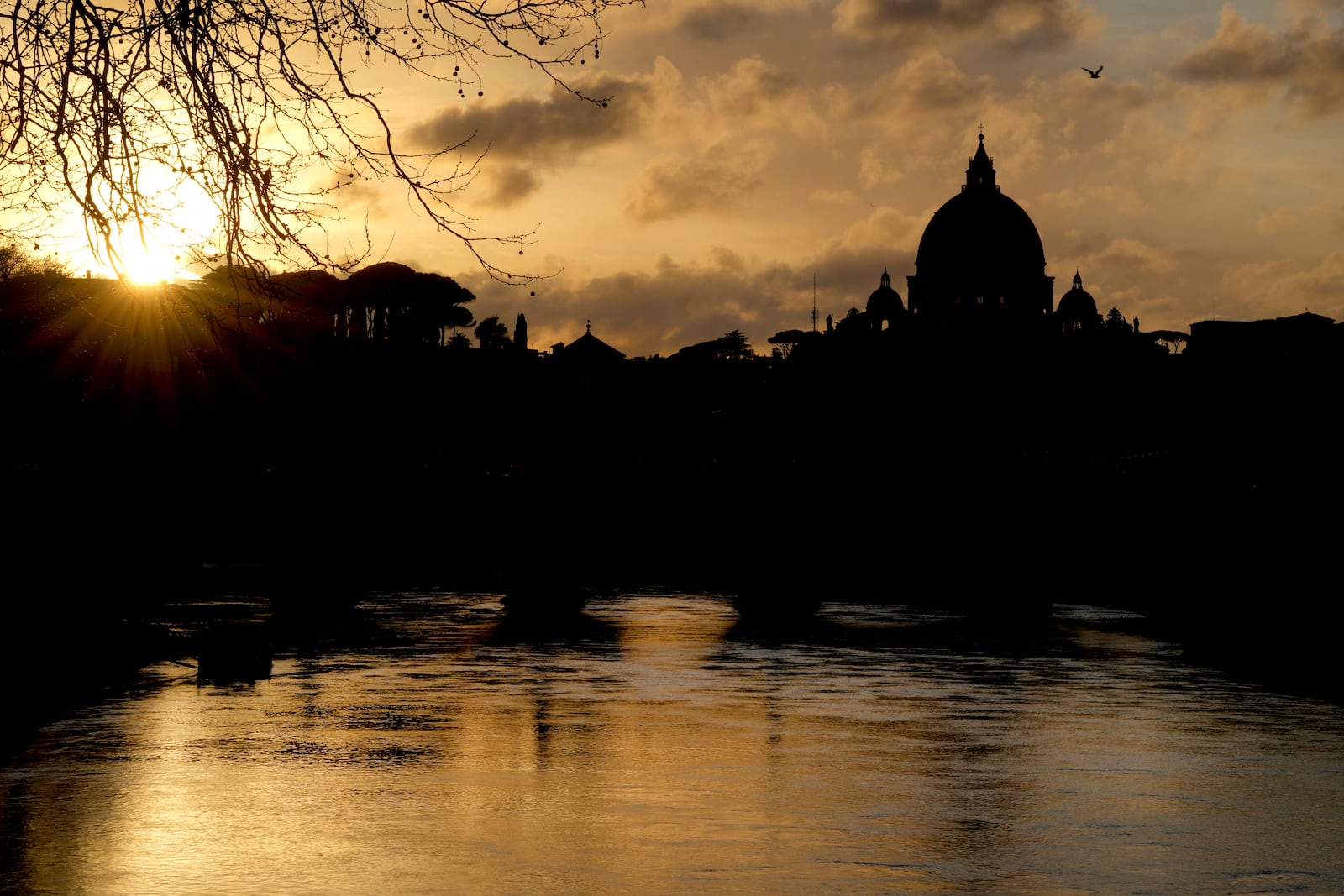 St Peter's Basilica at The Vatican is silhouetted as the sun sets across the river Tiber in Rome, Italy Friday, Feb. 28, 2025. (AP Photo/Kirsty Wigglesworth)