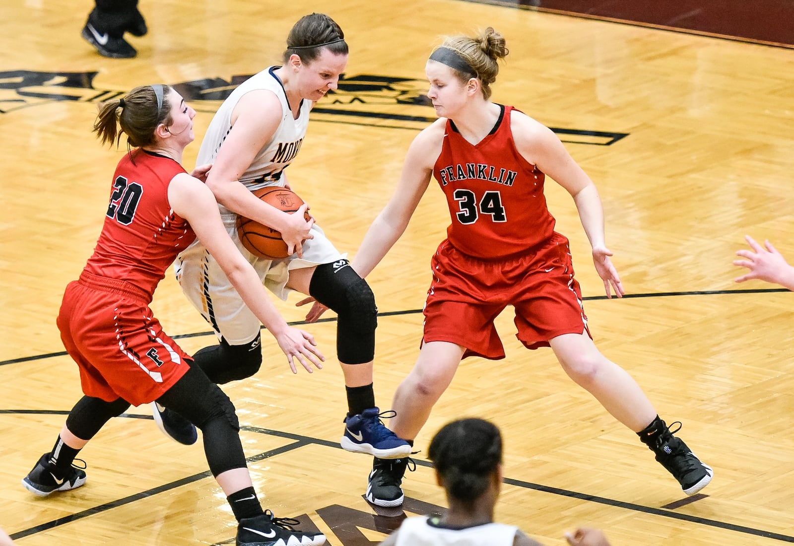 Monroe’s Sophie Sloneker drives to the hoop between Franklin’s Skyler Weir (20) and Brooke Stover (34) during Monday night’s Division II sectional final at Lebanon. NICK GRAHAM/STAFF