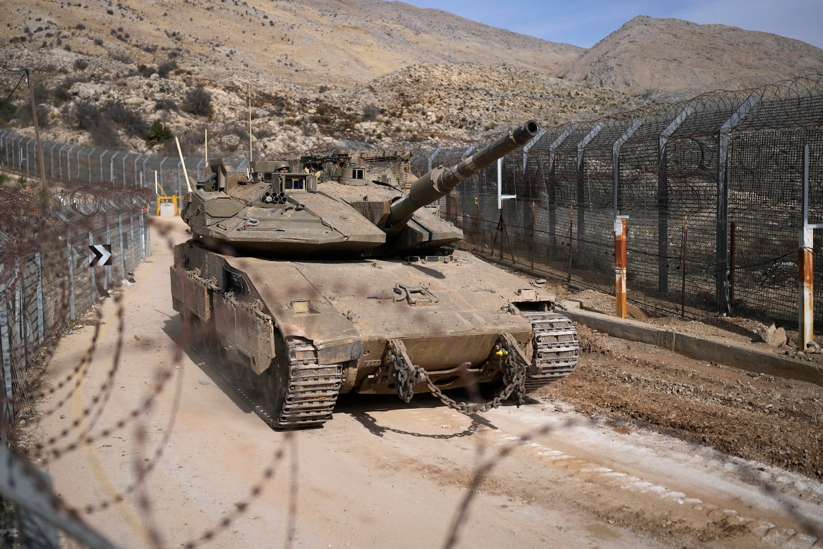 An Israeli tank maneuvers next to the security fence near the so-called Alpha Line that separates the Israeli-annexed Golan Heights from Syria, in the town of Majdal Shams, Wednesday, Dec. 11, 2024. (AP Photo/Matias Delacroix)