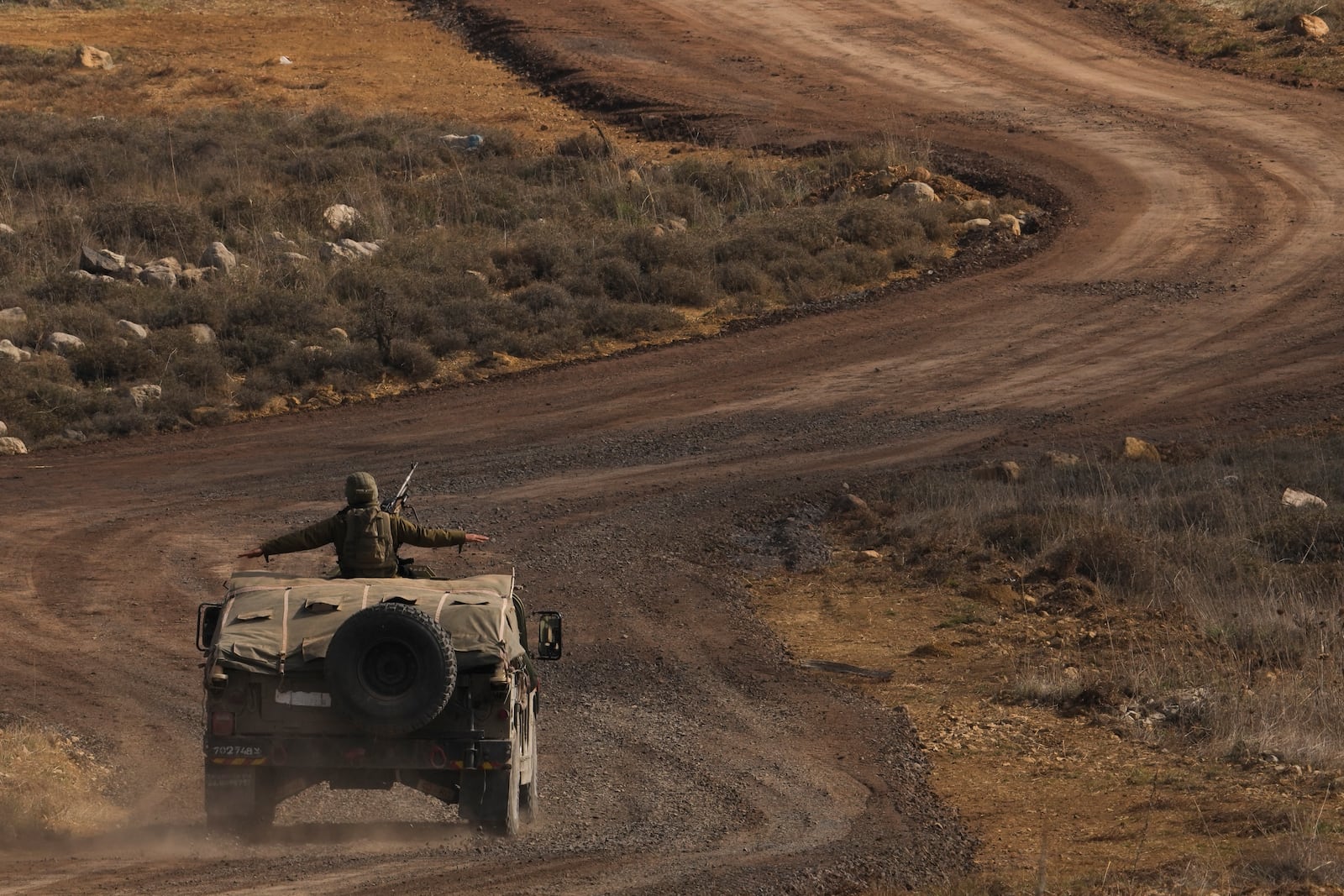 An Israeli soldier stands on an armoured vehicle on the buffer zone after crossing the security fence near the so-called Alpha Line that separates the Israeli-controlled Golan Heights from Syria, viewed from the town of Majdal Shams, Saturday, Dec. 21, 2024. (AP Photo/Matias Delacroix)