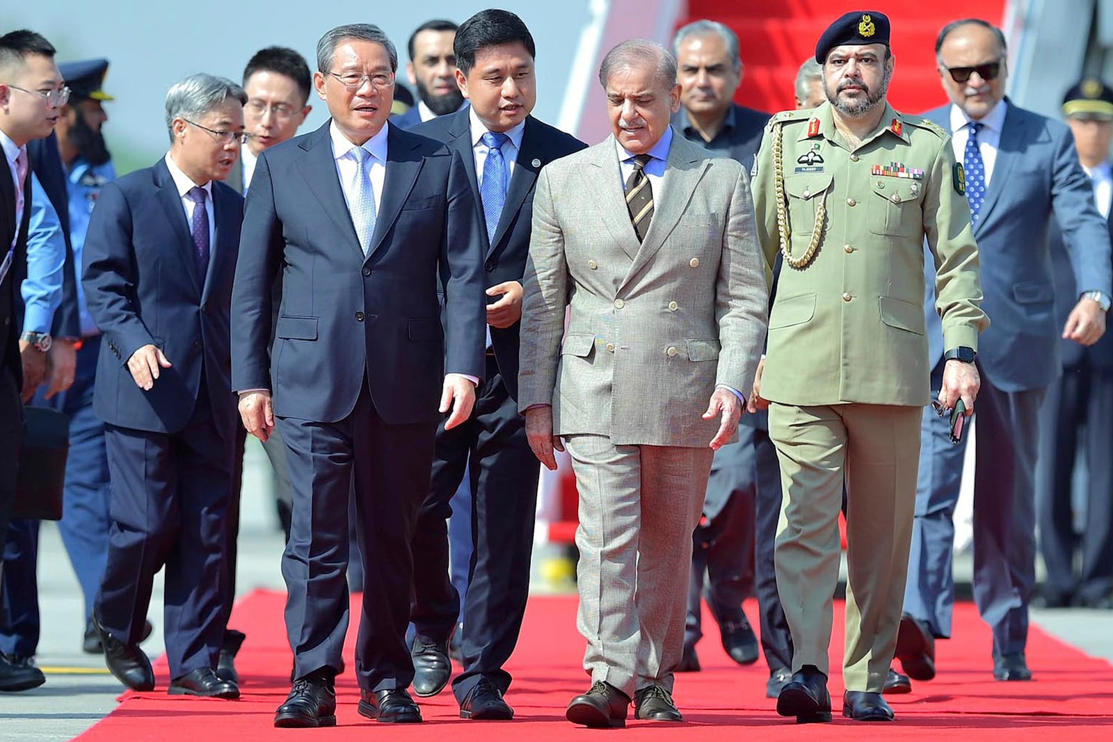 In this photo released by the Press Information Department, China's Premier Li Qiang, third left, walks Pakistan's Prime Minister Shehbaz Sharif, third right, upon his arrival at an airbase in Rawalpindi, Pakistan, Monday, Oct. 14, 2024. (Press Information Department via AP)