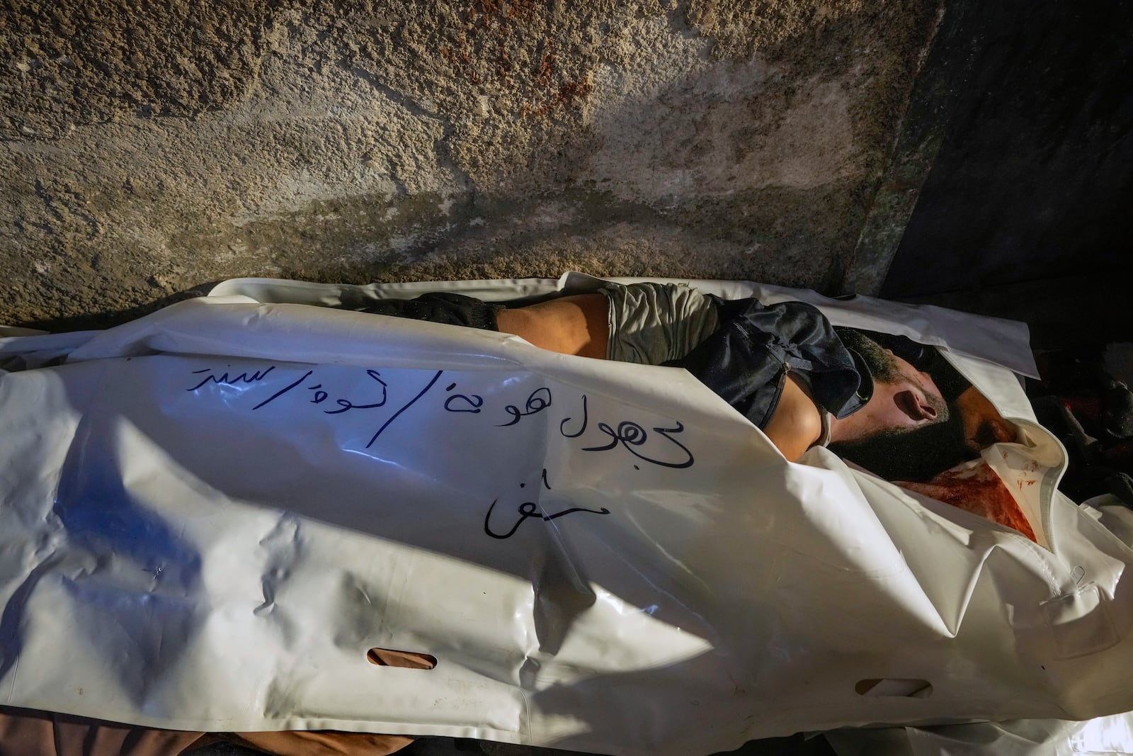 EDS NOTE: GRAPHIC CONTENT - A body wrapped in a plastic bag with the words "unknown identity" written in Arabic on it, lies on the floor of the morgue at the Al-Mojtahed hospital in Damascus, Syria, on Wednesday, Dec. 11, 2024. Many are flocking to morgues, hoping to identify loved ones who have been killed or were imprisoned under the rule of President Bashar Assad, whose government collapsed over the weekend.(AP Photo/Hussein Malla)