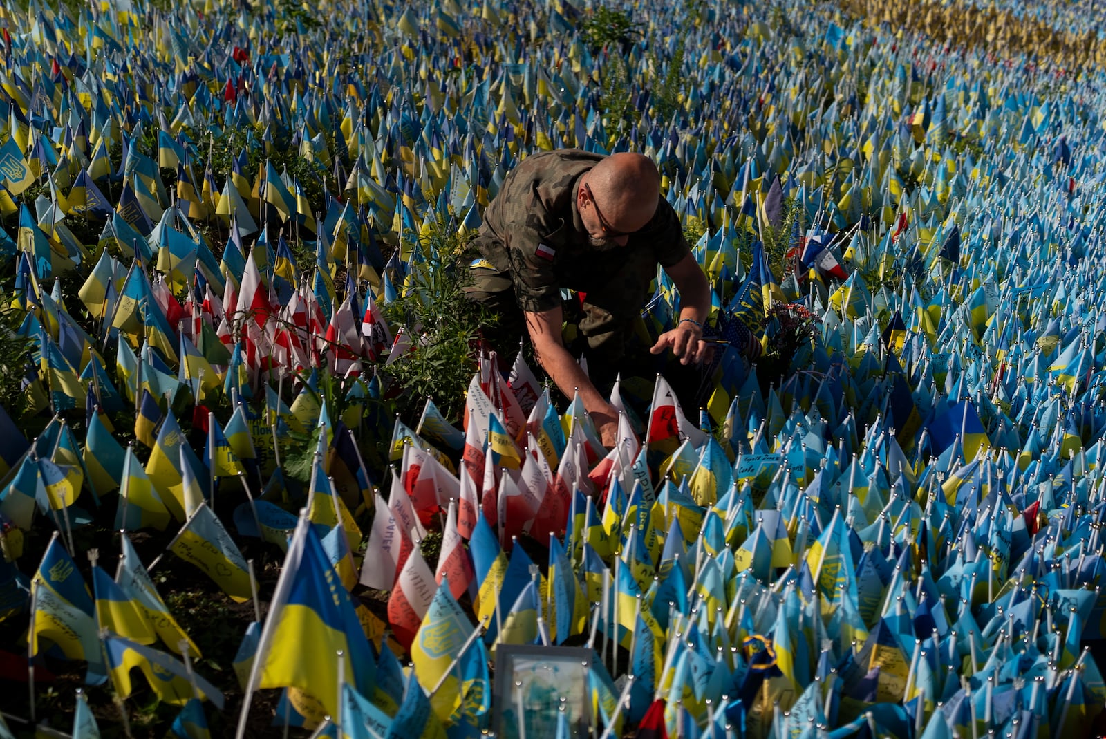 Polish Army veteran Slawomir Wysocki, 50, places the country's flag at a memorial site in Independence Square Kyiv, Ukraine, Wednesday, July 12, 2023, to honor a Polish paramedic killed in Ukraine's war against Russia. (AP Photo/Jae C. Hong)