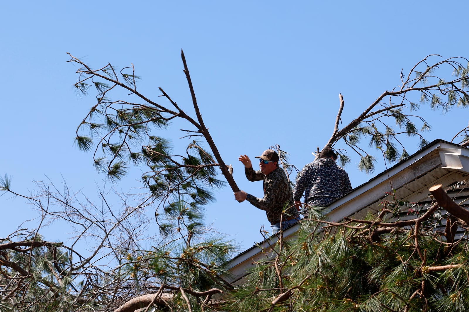 Friends and family members remove trees from a house after a tornado passed through the area Sunday, March 16, 2025, in Plantersville, Ala. (AP Photo/Butch Dill)