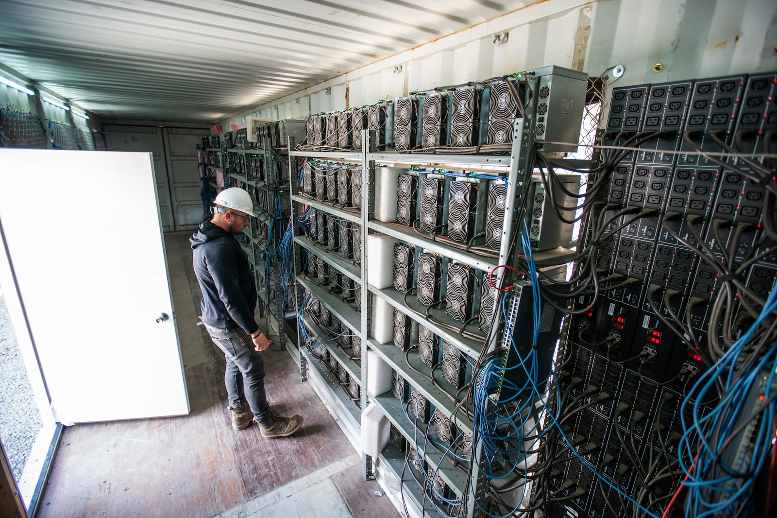 FILE - Chris Radwanski, data center supervisor, checks on Bitcoin mining machines in a shipping container behind the Scrubgrass Power plant in Russellton, Pa., July 23, 2021. (Andrew Rush/Pittsburgh Post-Gazette via AP, File)