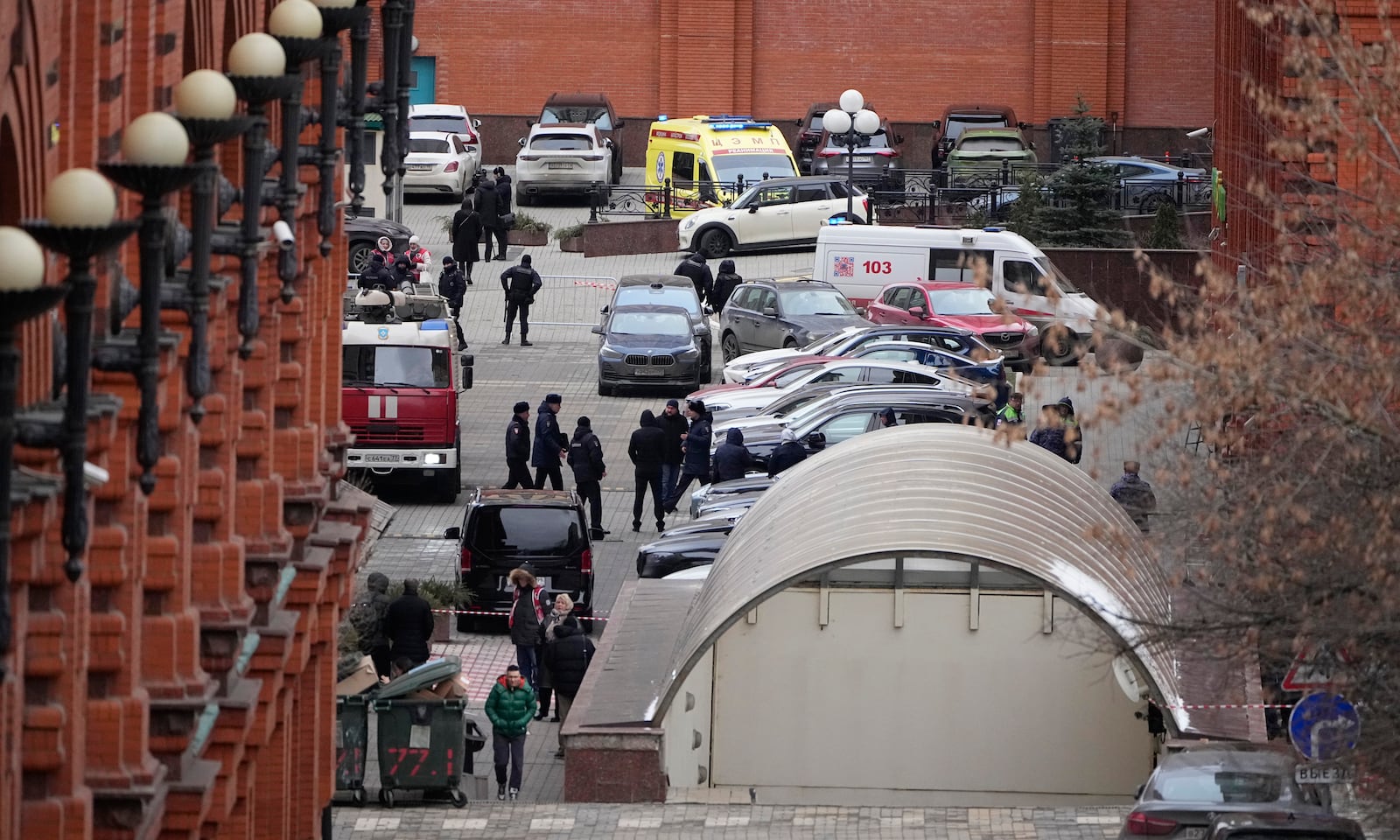 Investigators and police officers stand in the yard of an upscale residential block in Moscow, Russia, Monday, Feb. 3, 2025, where the blast has killed one person and wounded four others, Russian news agencies say. (AP Photo/Alexander Zemlianichenko)