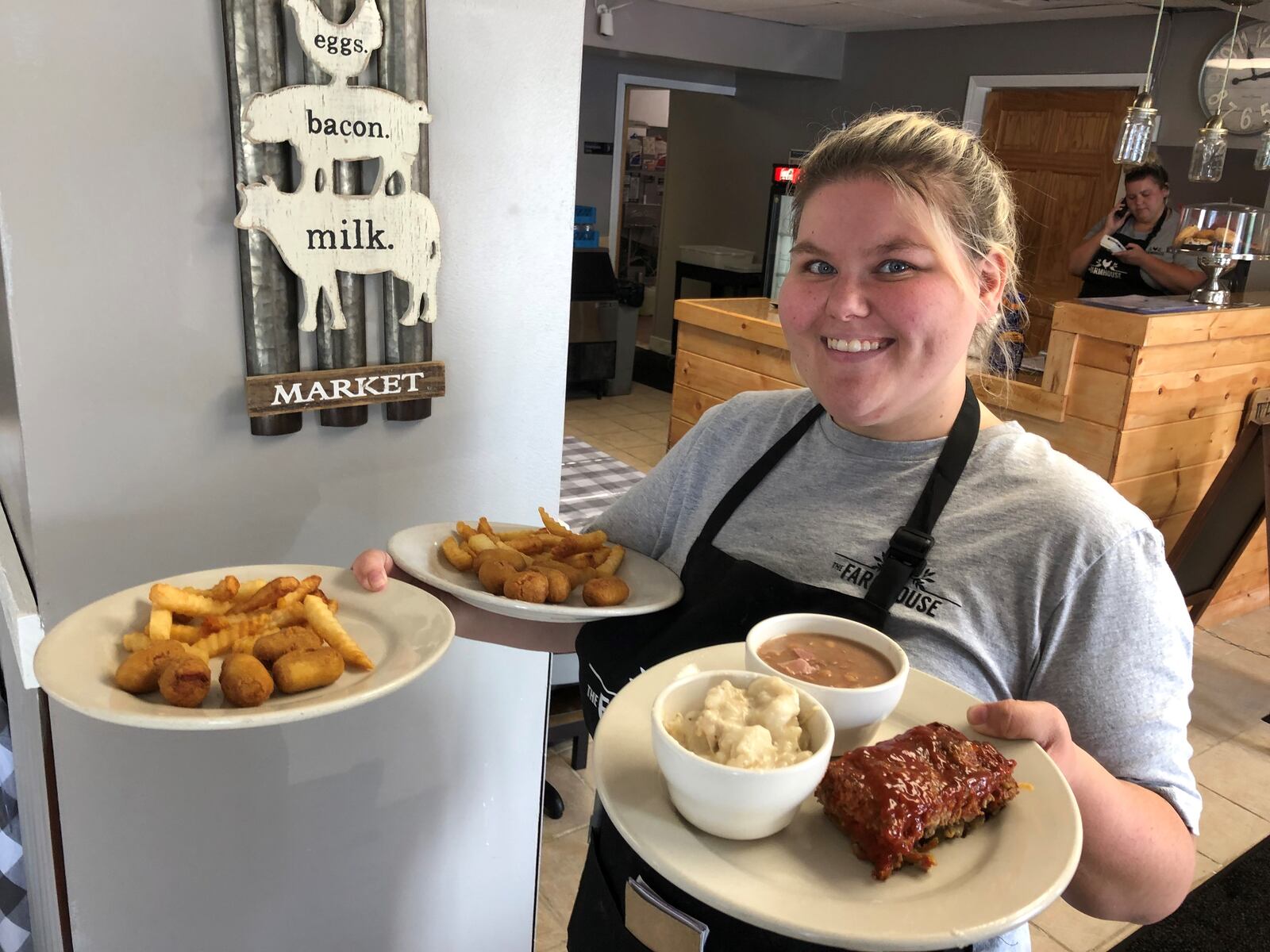 Barb Nease, who co-owns Farmhouse Diner in Trenton with her mother, delivers plates of food to customers Monday morning. The restaurant has been open for one week and because of a shortage of employees has reduced its hours. RICK McCRABB/STAFF