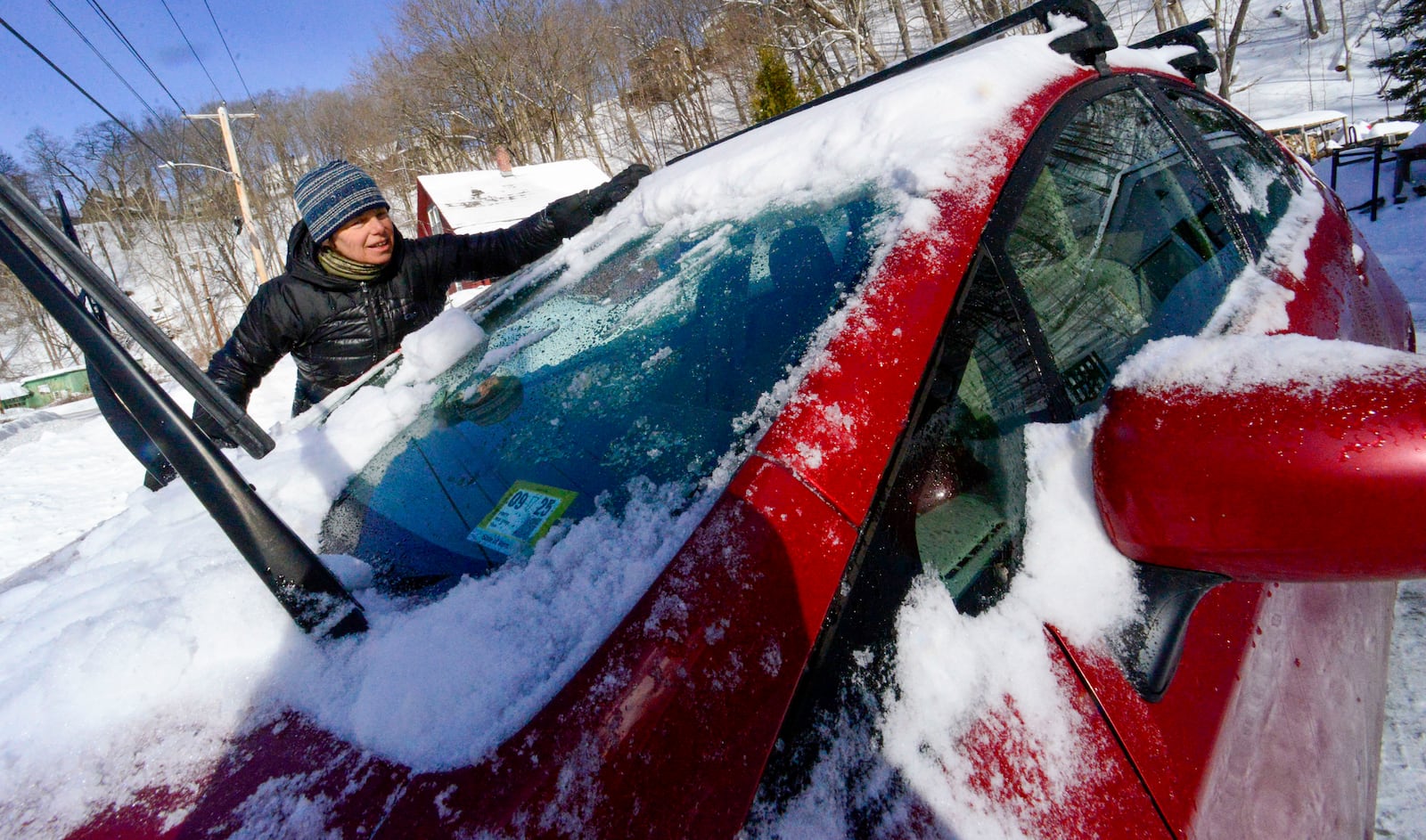 Kathy Carr uses her hands to remove the ice chunks on her vehicle on Monday, Feb. 17, 2025, Brattleboro, Vt. after a winter storm on Sunday. (Kristopher Radder/The Brattleboro Reformer via AP)