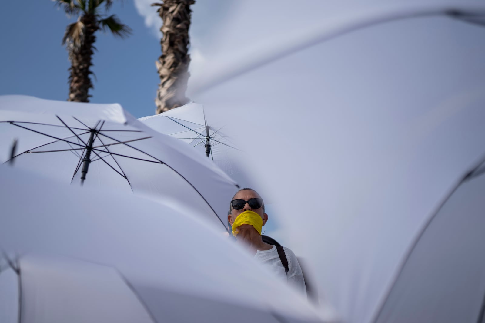 An activist with a yellow ribbon on her mouth holds a white umbrella during a protest calling for the release of hostages held in the Gaza Strip, in front of the U.S. Embassy branch office in Tel Aviv, Israel, Friday, Jan. 31, 2025. (AP Photo/Oded Balilty)