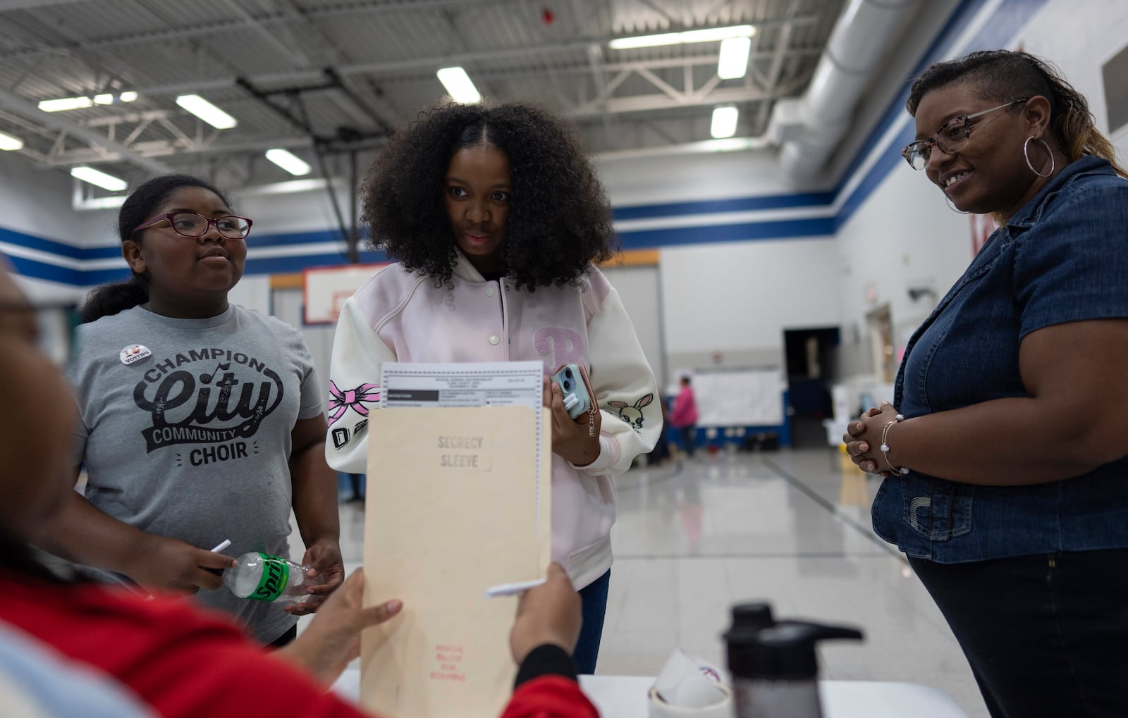 First-time voter Samaira Peterson, center, stands with her mother Khayesha Peterson, right, and her little sister Samaiya Peterson, left, as she prepares to vote at Warder Park-Wayne Elementary School on Election Day, Tuesday, Nov. 5, 2024, in Springfield, Ohio. (AP Photo/Carolyn Kaster)