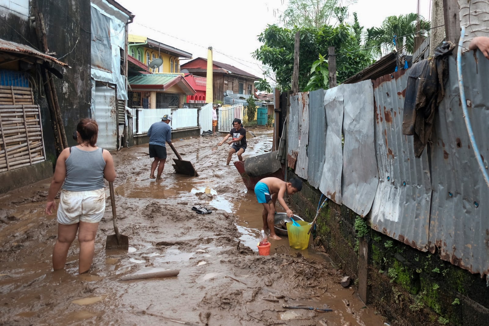 Residents collect mud as they start cleaning their area after floods caused by Tropical Trami, locally named Kristine, hit in Polangui, Albay province, Philippines on Oct. 23, 2024. (AP Photo/John Michael Magdasoc)