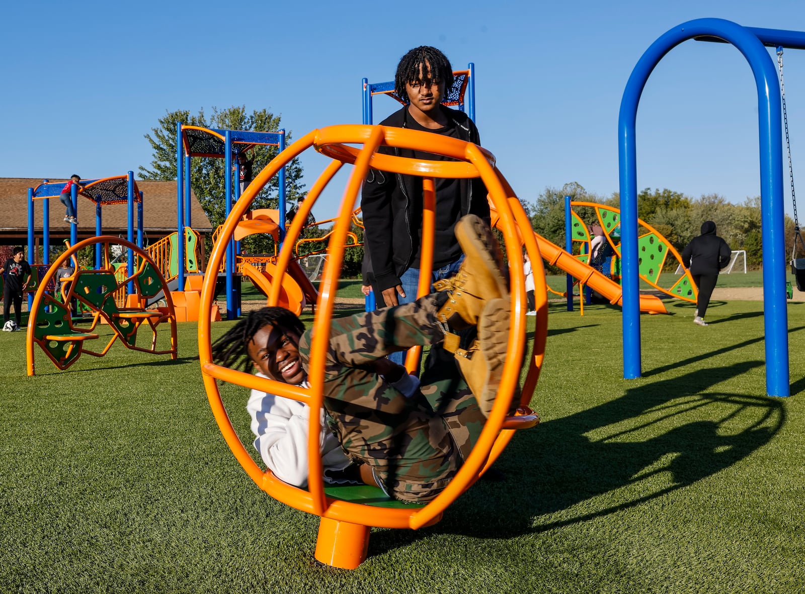 William Phipps, 15, spins King Steele, 15, at the new playground at Liberty Park Thursday, Oct. 17, 2024 on Yankee Road in Liberty Township. NICK GRAHAM/STAFF