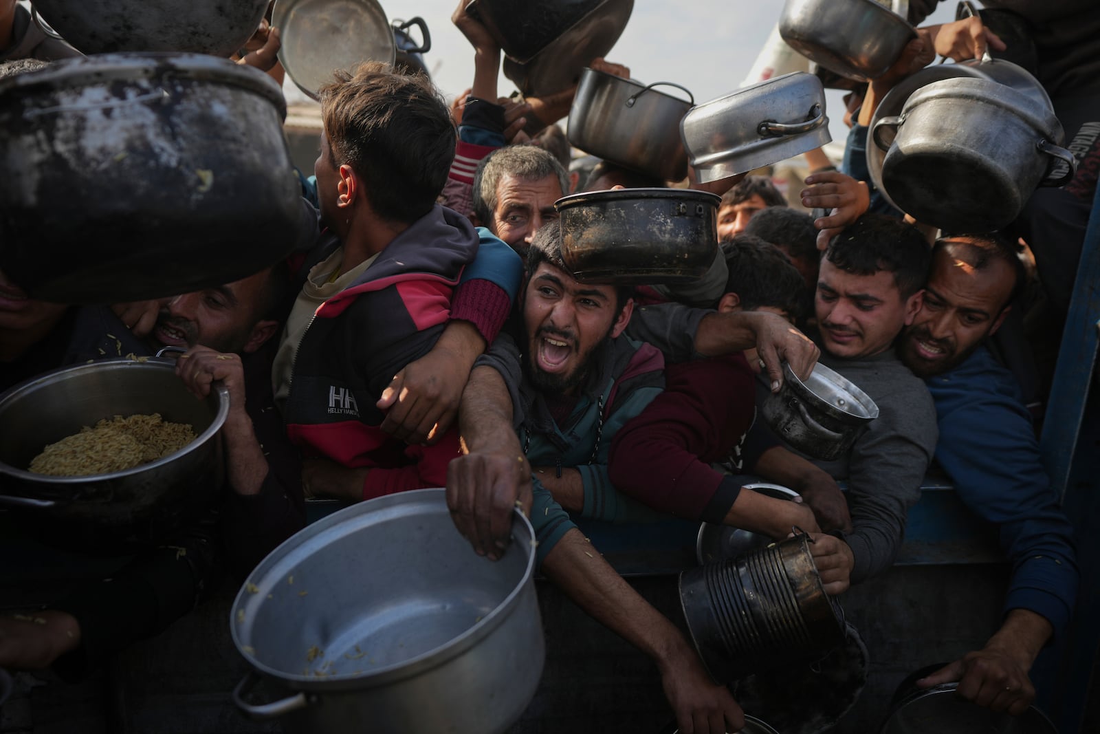 Palestinians struggle to reach for food at a distribution center in Khan Younis, Gaza Strip, Friday, Jan. 9, 2025. (AP Photo/Abdel Kareem Hana)