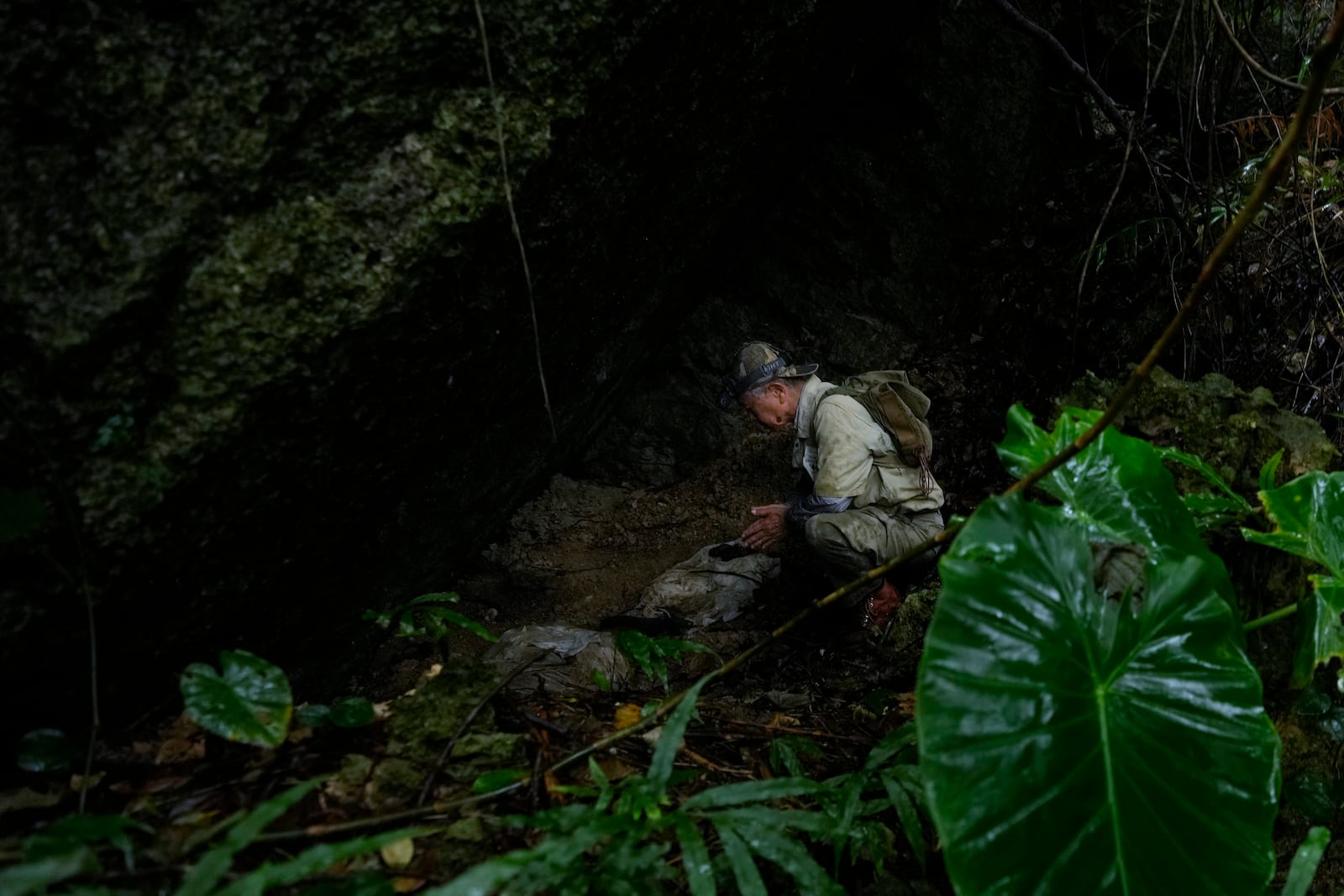 Takamatsu Gushiken prays before the remains of those who died during the Battle of Okinawa towards the end of the World War II in 1945, that he found in the past and temporarily kept in a cave before searching again at the cave in Itoman, on the main island of the Okinawa archipelago, southern Japan, Sunday, Feb. 16, 2025. (AP Photo/Hiro Komae)