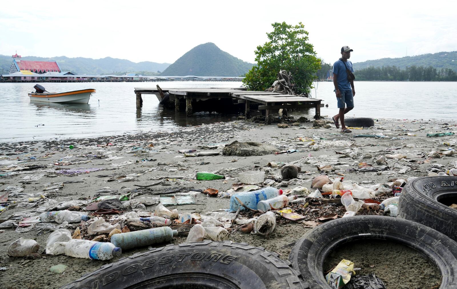 FILE - A man walks past plastic waste strewn along at Enggros village beach in Jayapura, Papua province, Indonesia, Oct. 2, 2024. (AP Photo/Firdia Lisnawati, File)