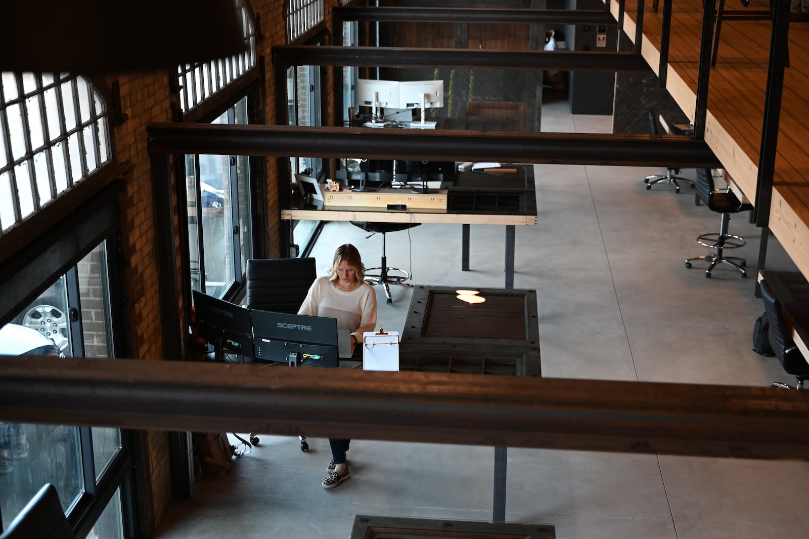 A tour of the Meyer Brothers and Sons recently remodeled facility on Maple Avenue in the Jefferson neighborhood of Hamilton. They spent about a year remodeling the old freight depot into a showroom and workshop. Pictured on May 10, 2024, is Cari Bolte, a senior kitchen designer, working at one of the desks that used old doors from the historic building. MICHAEL D. PITMAN/STAFF