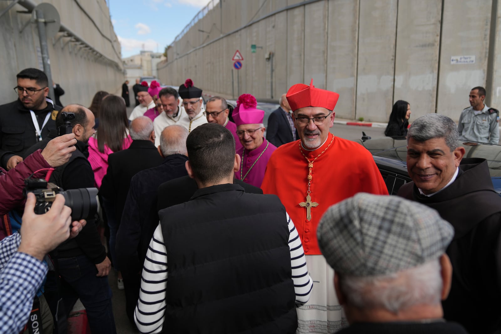 Archbishop Pierbattista Pizzaballa, the top Roman Catholic cleric in the Holy Land, is received by local community while crossing an Israeli military checkpoint from Jerusalem for Christmas Day celebrations at the Church of the Nativity, traditionally recognized by Christians to be the birthplace of Jesus Christ, in the West Bank city of Bethlehem Tuesday, Dec. 24, 2024. (AP Photo/Nasser Nasser)