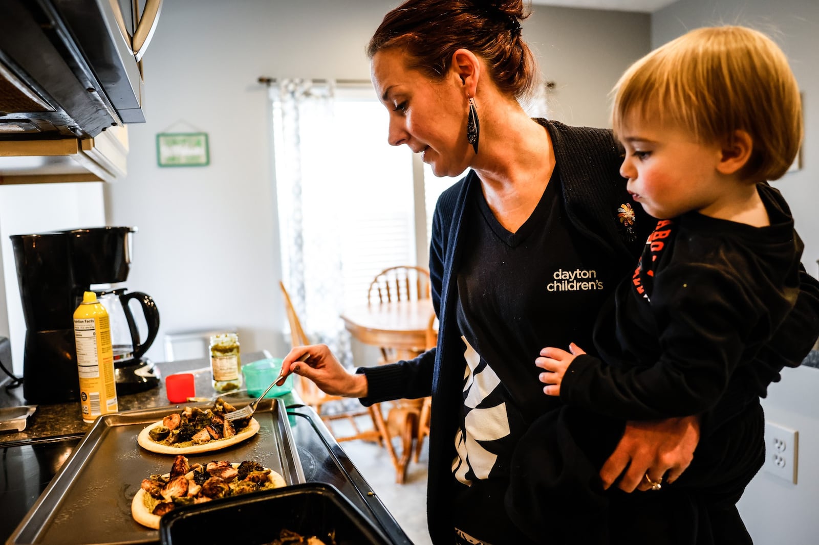 Kristen Bowser and her 18-month-old son, Andrew, whip-up food in the kitchen of their home in Springboro. Bowser is a working mother of 5, who said the family is paying higher prices for groceries, gas and a new vehicle because of inflation. JIM NOELKER/STAFF JIM NOELKER/STAFF