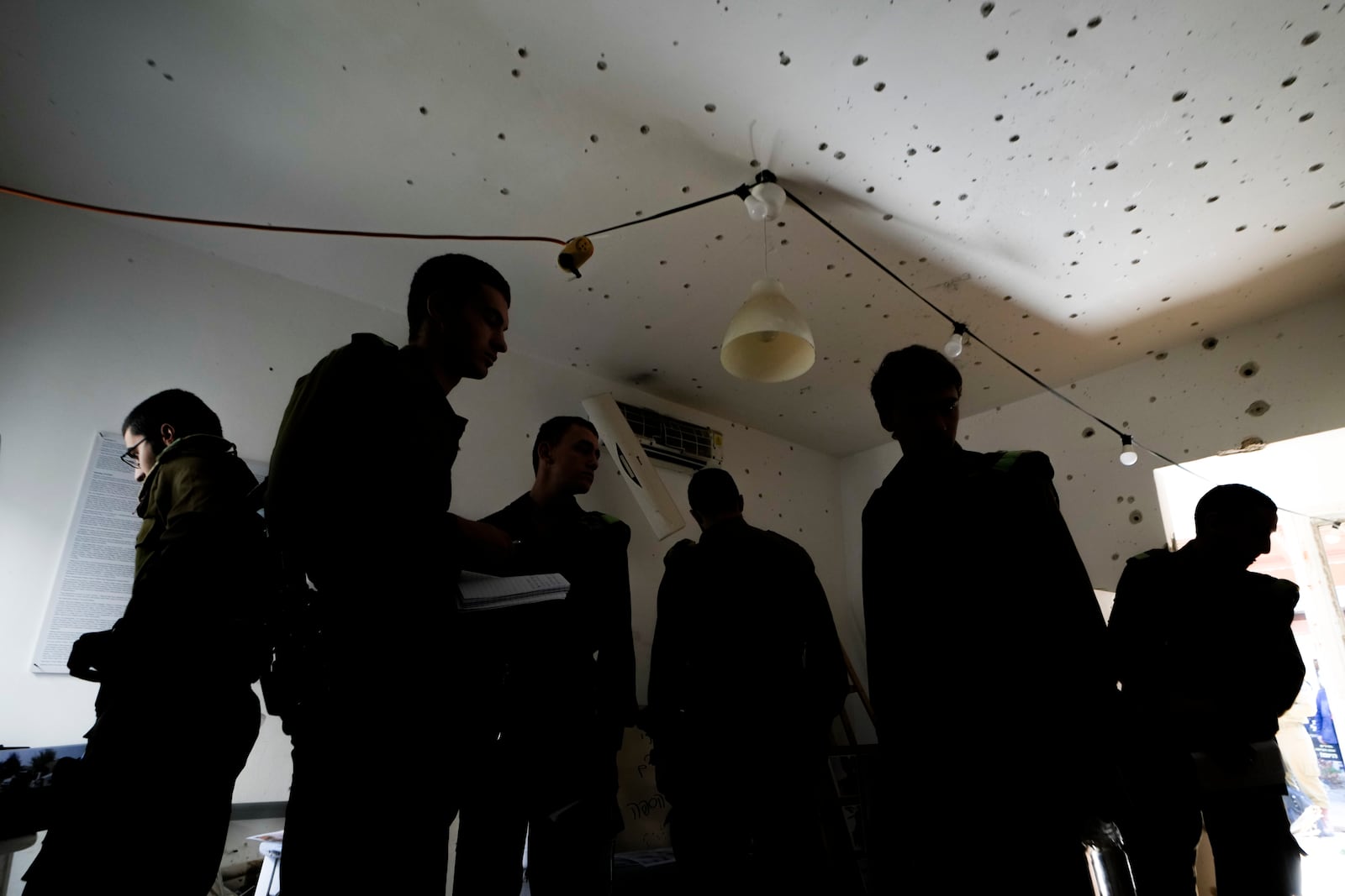 Israeli soldier stand in a bullet-ridden house during a tour for army personnel to observe the damage caused by the Oct. 7 Hamas onslaught at Kibbutz Kfar Aza, near the Israeli-Gaza border, in Israel, Thursday, Jan. 2, 2025. (AP Photo/Matias Delacroix)