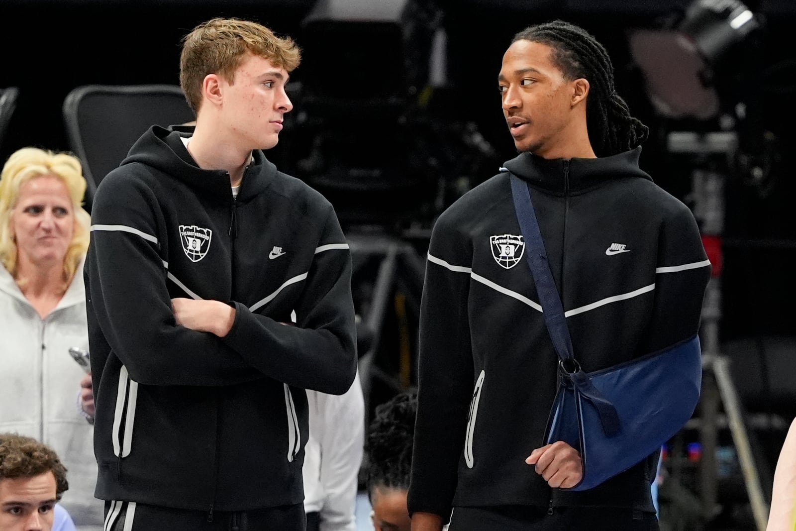 Duke forward Cooper Flagg, left, and forward Maliq Brown watch warms ups before an NCAA college basketball game against North Carolina in the semifinals of the Atlantic Coast Conference tournament, Friday, March 14, 2025, in Charlotte, N.C. Flagg and Brown were injured yesterday. (AP Photo/Chris Carlson)