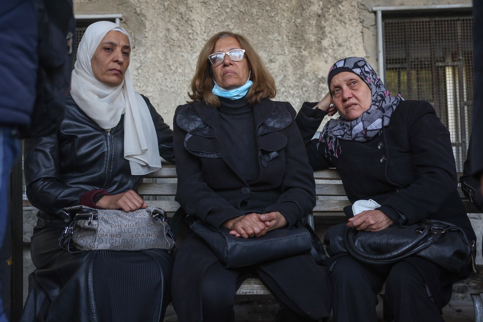 Three women wait outside the morgue to identify missing relatives or friends at the Al-Mujtahidh hospital in Damascus, Syria, Tuesday, Dec. 10, 2024. (AP Photo/Ghaith Alsayed)