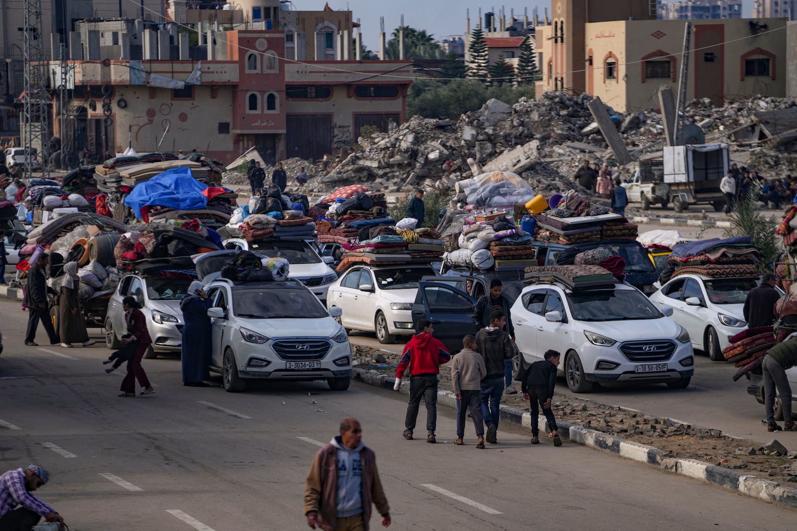 Displaced Palestinians with their belongings gather near a roadblock on Salah al-Din Street, as they wait to return to their homes in the northern part of the Gaza Strip, Sunday, Jan. 26, 2025, days after the ceasefire deal between Israel and Hamas came into effect. (AP Photo/Abdel Kareem Hana)