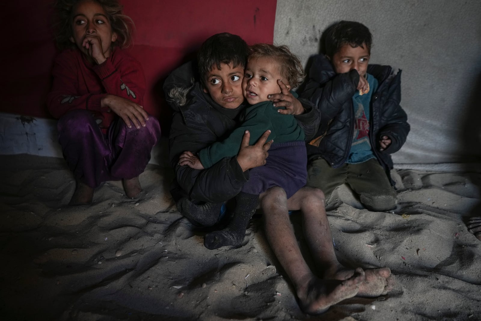 Palestinian Tamim Marouf, 6, sits inside his family's tent alongside his sister Hala, 10, and his brother Malek, 4, at a camp for internally displaced Palestinians on the beachfront in Deir al-Balah, central Gaza Strip, Friday, Dec. 27, 2024. (AP Photo/Abdel Kareem Hana)