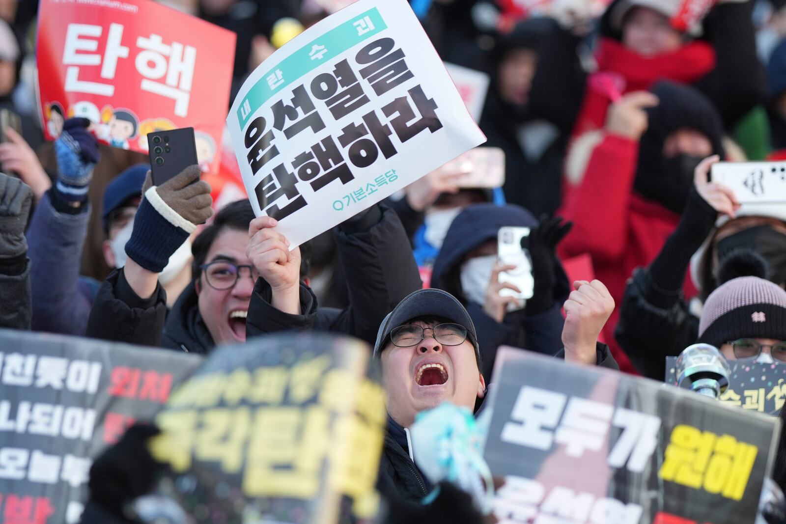 Participants react after hearing the news that South Korea's parliament voted to impeach President Yoon Suk Yeol outside the National Assembly in Seoul, South Korea, Saturday, Dec. 14, 2024. The letters read "Impeachment Yoon Suk Yeol." (AP Photo/Lee Jin-man)