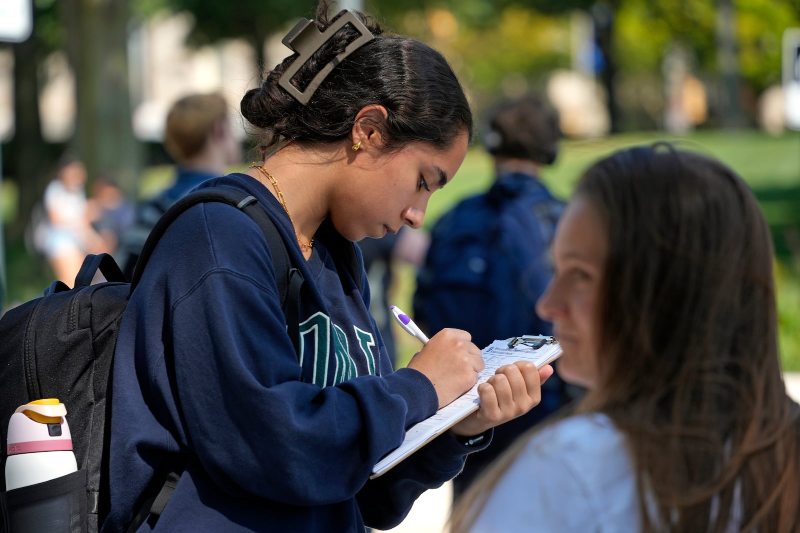 University of Pittsburgh freshman Teba Latef, left, fills out a voter registration form on Thursday, Sept. 12, 2024, at a voter registration table on campus in Pittsburgh run by NextGen America, a progressive organization that's trying to increase turnout among young women in battleground states like Pennsylvania. (AP Photo/Gene J. Puskar)