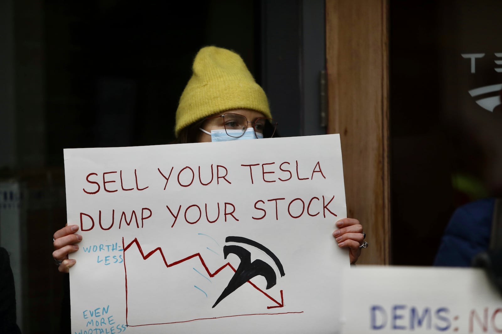 A person protesting Elon Musk's actions in the Trump administration holds a sign outside a Tesla showroom in Seattle on Thursday, Feb. 13, 2025. (AP Photo/Manuel Valdes)