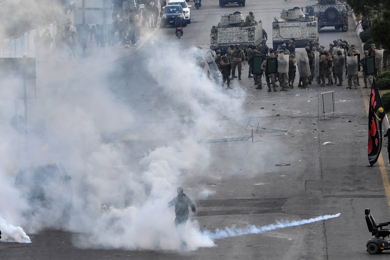 A protester covered by the smoke of tear gas that fired by Lebanese army against Hezbollah supporters, who were protesting near Beirut's international airport against Lebanon's decision to revoke permission for an Iranian carrier after Israel accused Iran of smuggling cash to Hezbollah, in Beirut, Lebanon, Saturday, Feb. 15, 2025. (AP Photo)