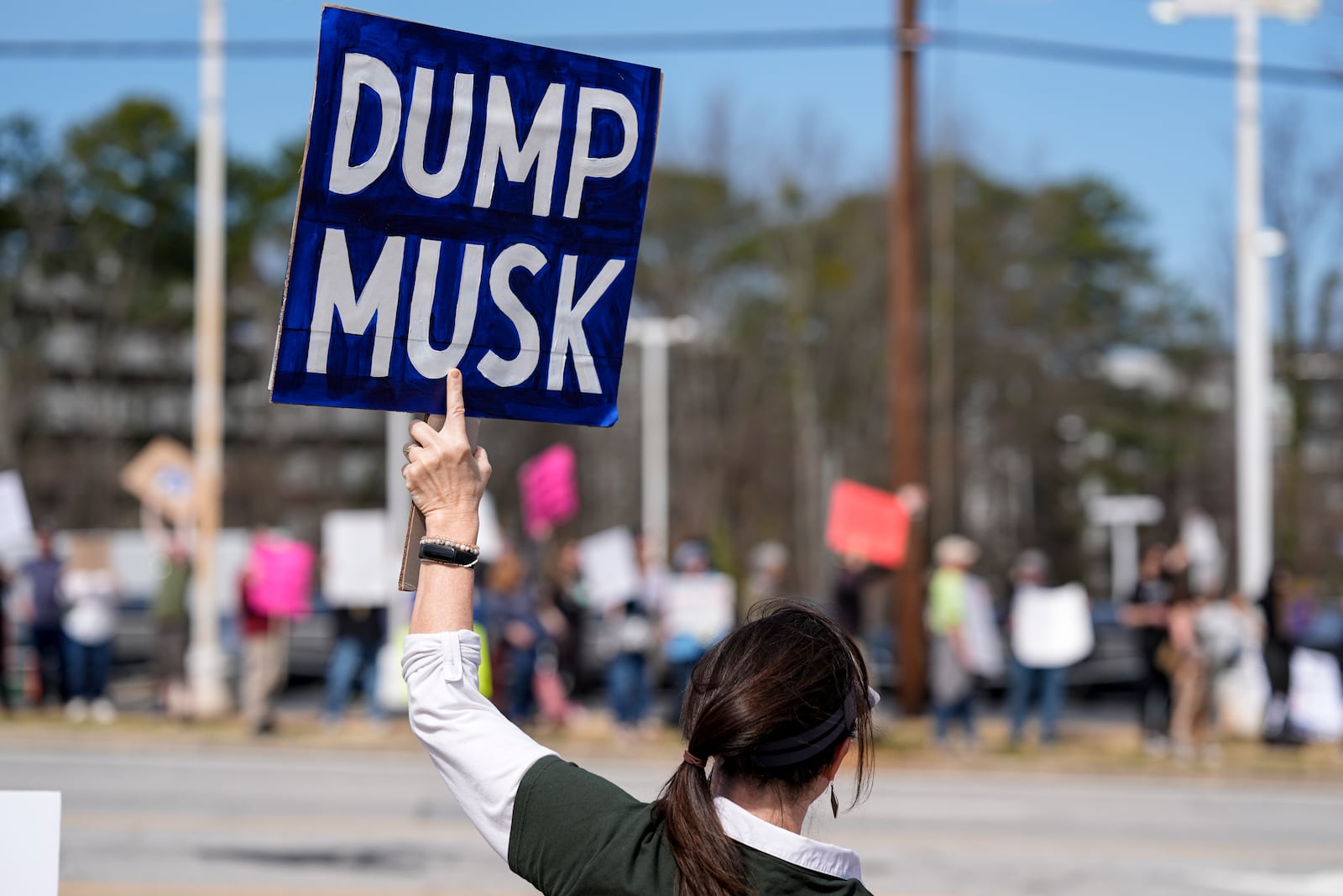 Korinna Hirsch stands with other demonstrators during a protest of automaker billionaire CEO, Elon Musk near a Tesla vehicle dealership, Saturday, March 8, 2025, in Decatur, Ga. (AP Photo/Mike Stewart)