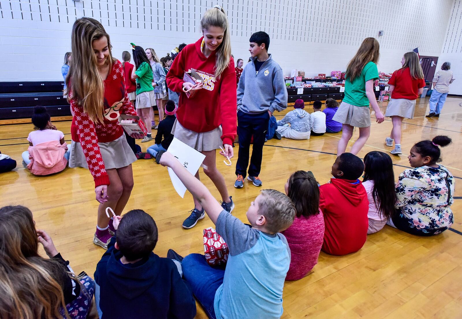 Fenwick sophomores Morgan Guyler, left, and Mackenzie Zlotnik hand out candy canes to students during a special event Wednesday, Dec. 19 at Rosa Parks Elementary School in Middletown. Students from Fenwick High School organized a toy drive to donate gifts to students at Rosa Parks Elementary School. Hundreds of presents were donated and each student at Rosa Parks received a gift Wednesday, Dec. 19. NICK GRAHAM/STAFF