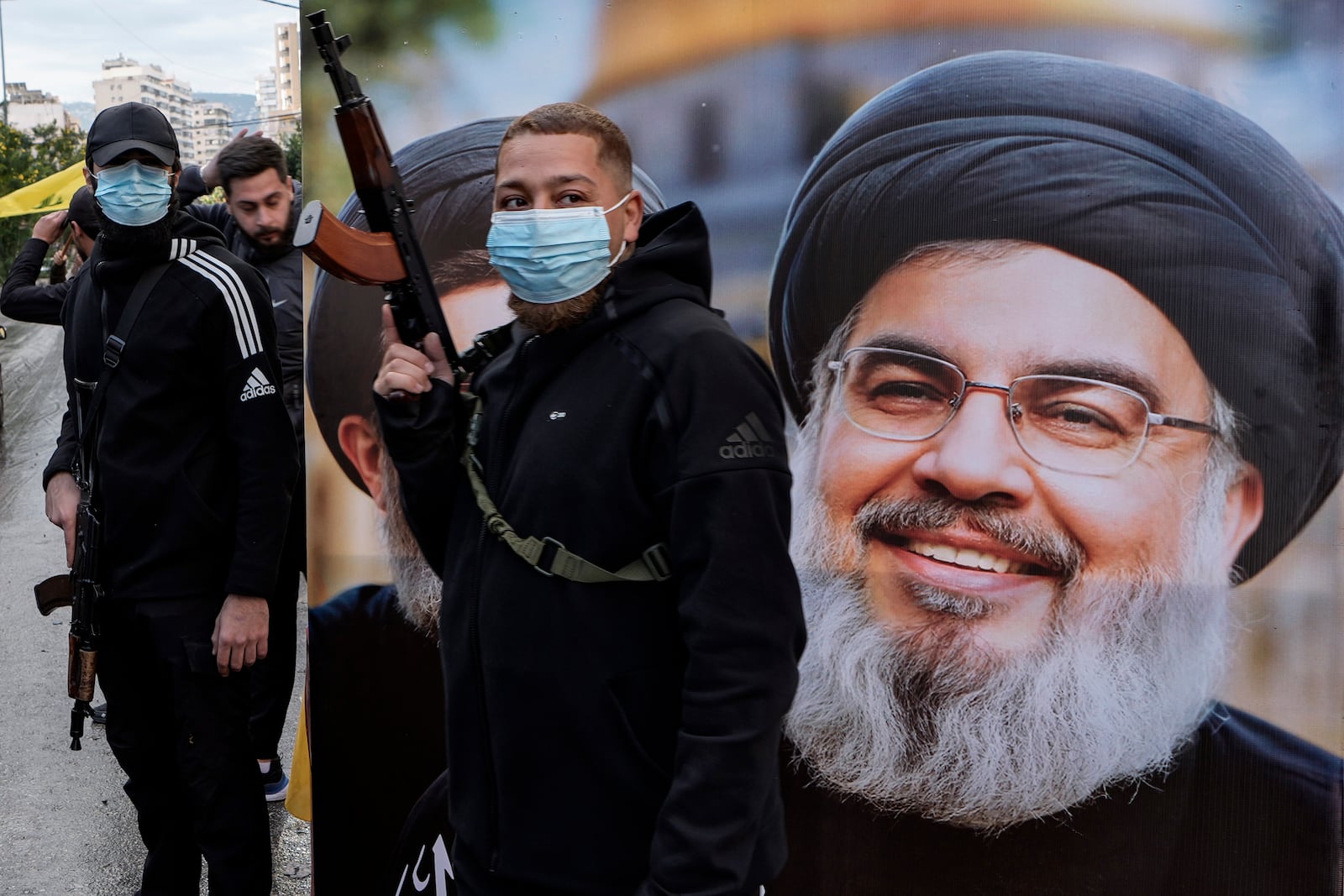 Hezbollah gunmen stand next to a poster of slain Hezbollah leader Hassan Nasrallah as displaced residents return to Dahiyeh, in Beirut, Lebanon, following a ceasefire between Israel and Hezbollah that went into effect on Wednesday, Nov. 27, 2024. (AP Photo/Bilal Hussein)