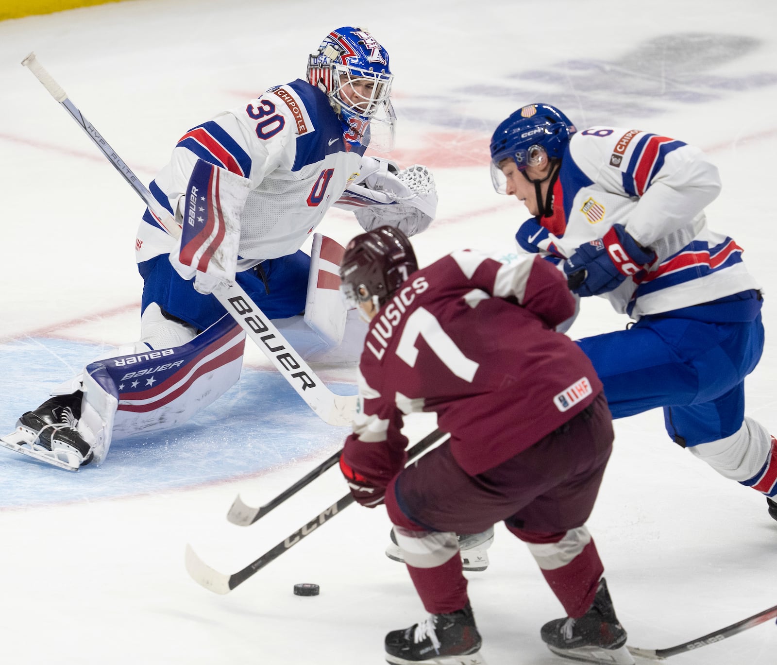 United States goaltender Hampton Slukynsky watches defenseman Adam Kleber, right, tie up Latvia forward Davis Livsics during the third period of a IIHF World Junior Hockey Championship tournament game, Saturday, Dec.28, 2024 in Ottawa, Ontario. (Adrian Wyld/The Canadian Press via AP)