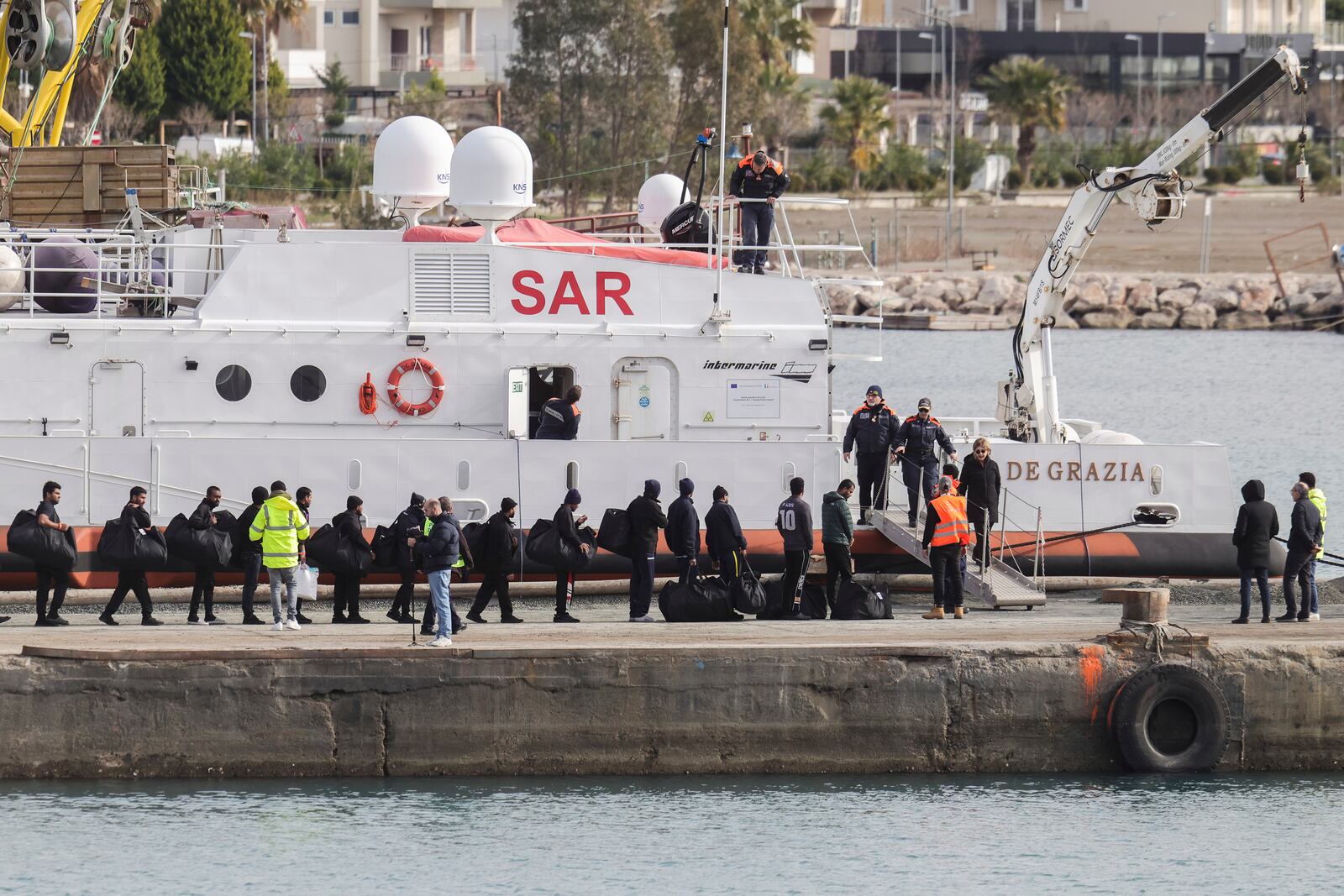 Migrants board an Italian Coast Guard vessel as part of a transfer operation from the asylum processing centers in Albania back to Italy following a court decision in Rome, at the port of Shengjin, northwestern Albania, Saturday, Feb. 1, 2025. (AP Photo/Vlasov Sulaj)