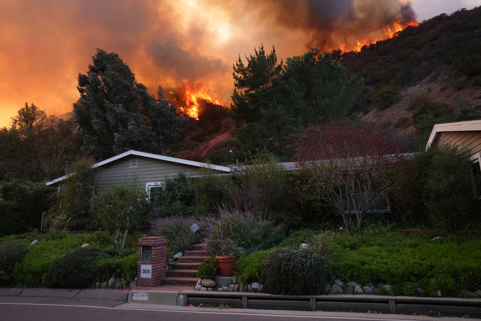 The Palisades Fire burns above a home in Mandeville Canyon, Saturday, Jan. 11, 2025, in Los Angeles. (AP Photo/Eric Thayer)