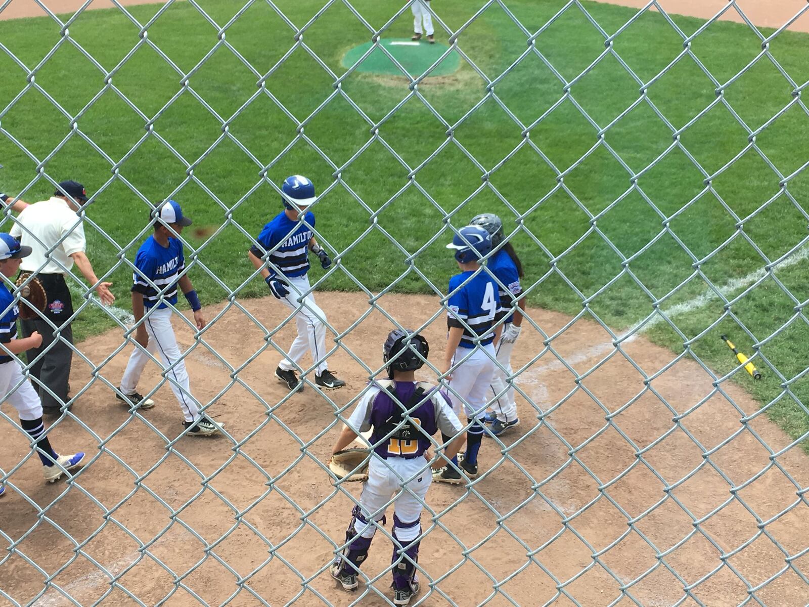 Hamilton West Side’s Lake Cundiff is about to be congratulated by Davis Avery (4) and Katelyn Polido after driving them in with a three-run homer Sunday at Ford Park in Maumee. West Side beat Maumee 13-4 in the Ohio Little League 12-year-old tournament. RICK CASSANO/STAFF