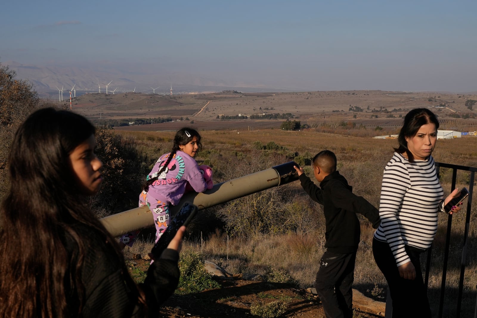 A girl plays atop a tank on display near the Syrian side of the Quneitra crossing, between Israel and Syria, as seen from the Israeli-occupied Golan Heights, Saturday, Dec. 14, 2024. (AP Photo/Matias Delacroix)