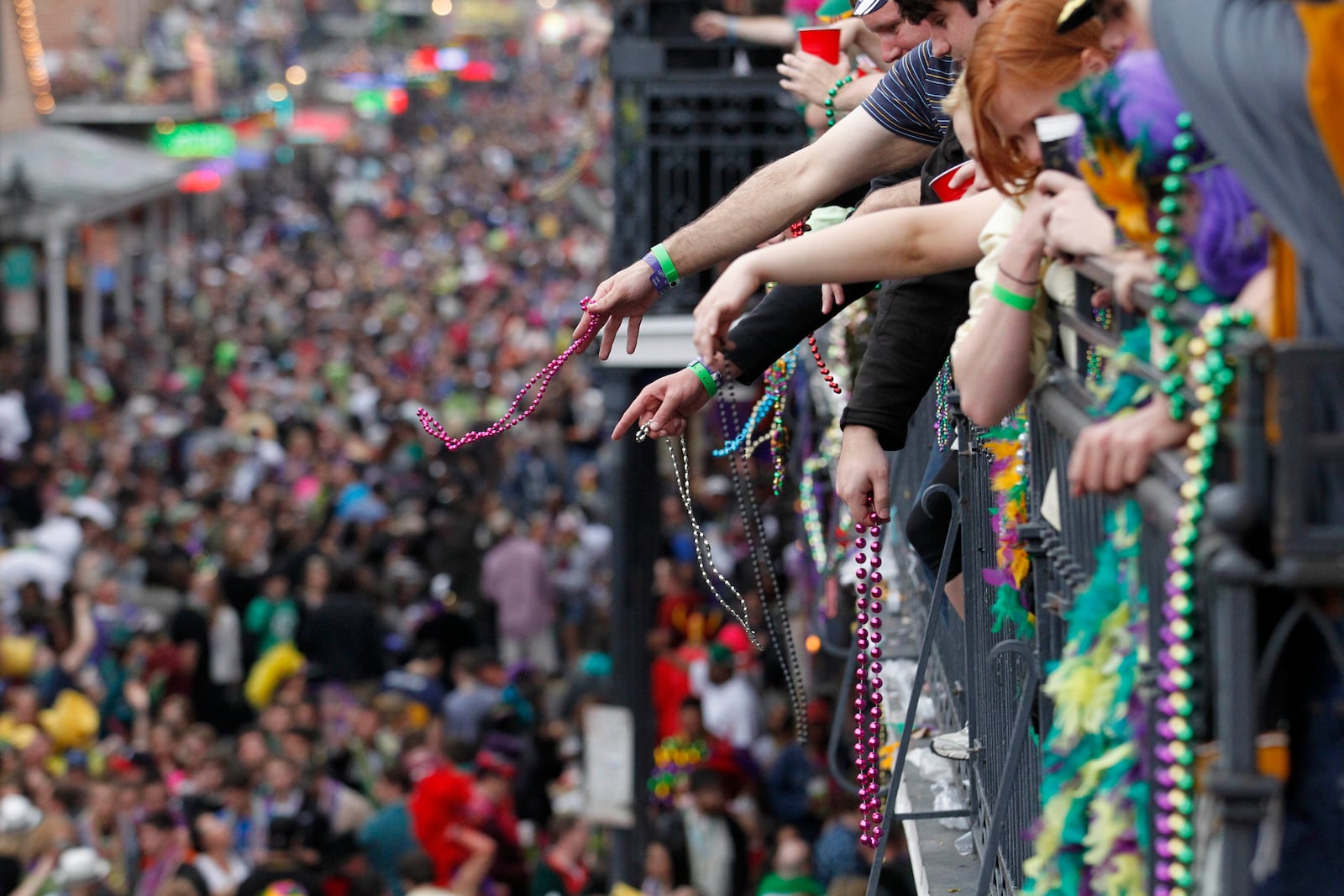 FILE - Revelers throw beads from the balcony of the Royal Sonesta Hotel onto crowds on Bourbon Street during Mardi Gras festivities in the French Quarter in New Orleans, March 8, 2011. (AP Photo/Gerald Herbert, File)